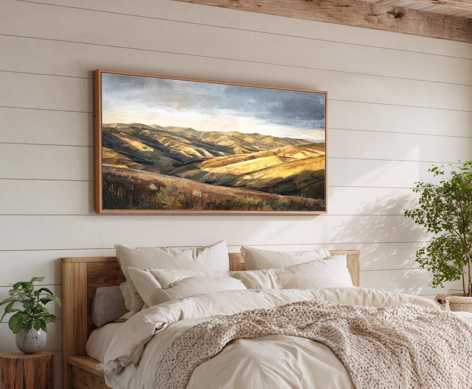 This horizontal art print features a muted palette with golden hues, depicting rolling hills and a dramatic sky in an impressionistic style, framed in natural wood. It is displayed above.