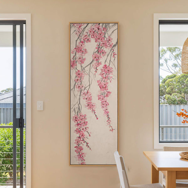 This vertical canvas print displays a traditional East Asian style painting of pink cherry blossoms cascading down branches with a light background, soft, textured neutral background, framed in natural wood.