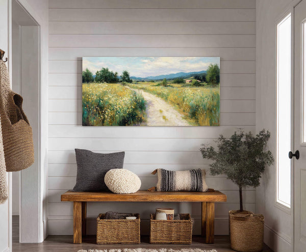 This horizontal canvas wall art features a plein air landscape painting of a dirt path winding through a field of wildflowers, with trees and distant hills under a pale blue.