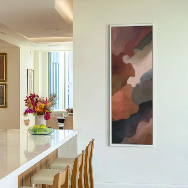 This vertical canvas wall art features an abstract design in earthy tones, framed with a thin white floater frame, and hangs on a white wall in what appears to be.