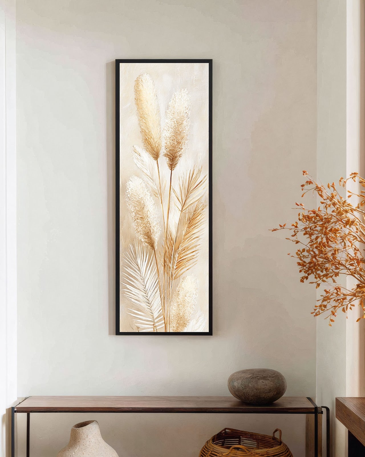 This vertical canvas wall art features textured botanical pampas grass in a beige palette, displayed in a black floater frame above a wooden console table against a beige hallway wall.