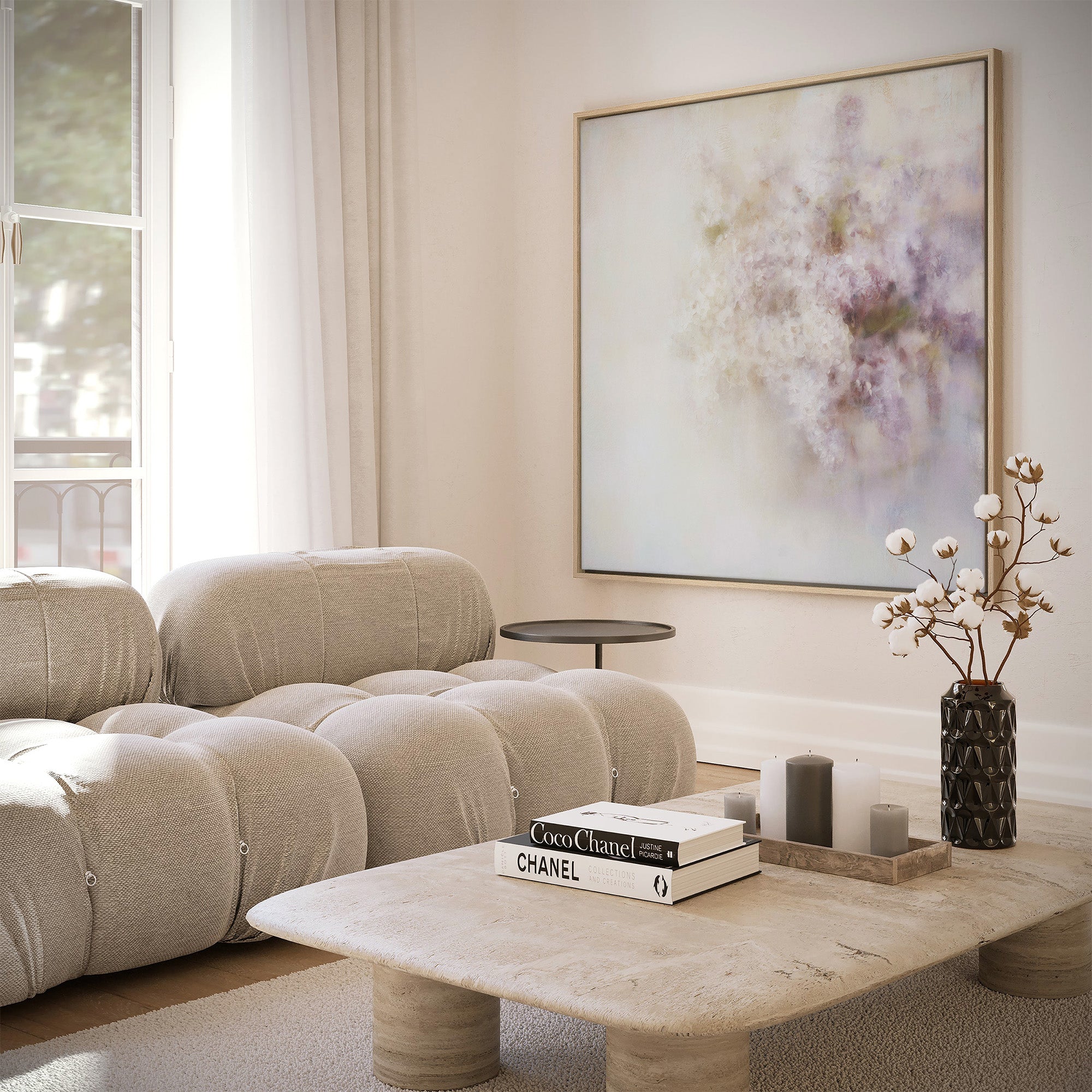 Large natural-framed abstract art print featuring soft, dreamlike clusters of white and purple lilac blooms against a hazy, light background, displayed on a white wall above a beige modular sofa and natural stone coffee table in a bright, modern living room.