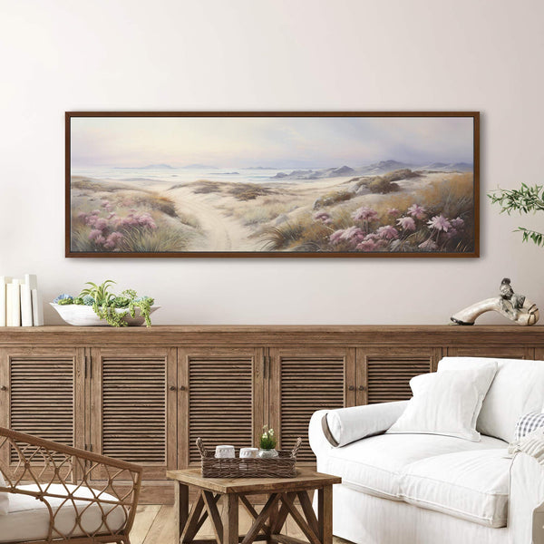 Framed landscape canvas wall art of coastal dunes and sea view displayed above a rustic wooden sideboard in a modern neutral living room