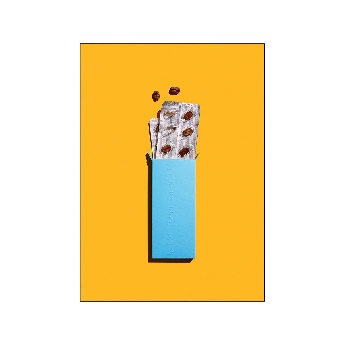 Blue coffee capsule box and silver blister packs on a vivid yellow background