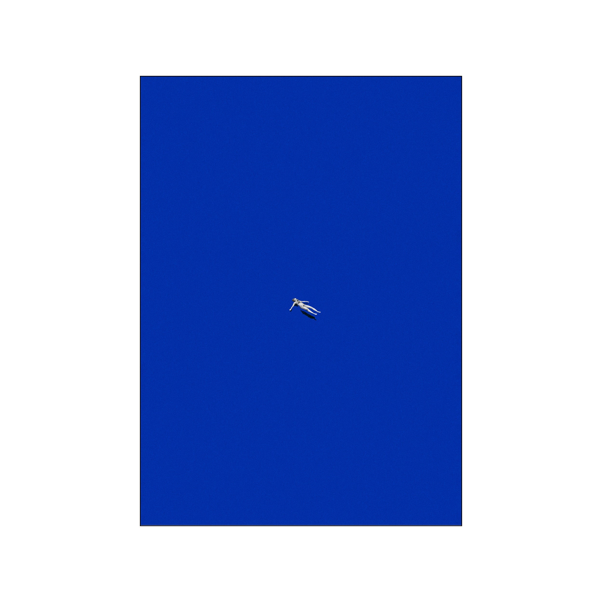 Lone white figure floating in a vast electric blue field with a calm, minimal composition