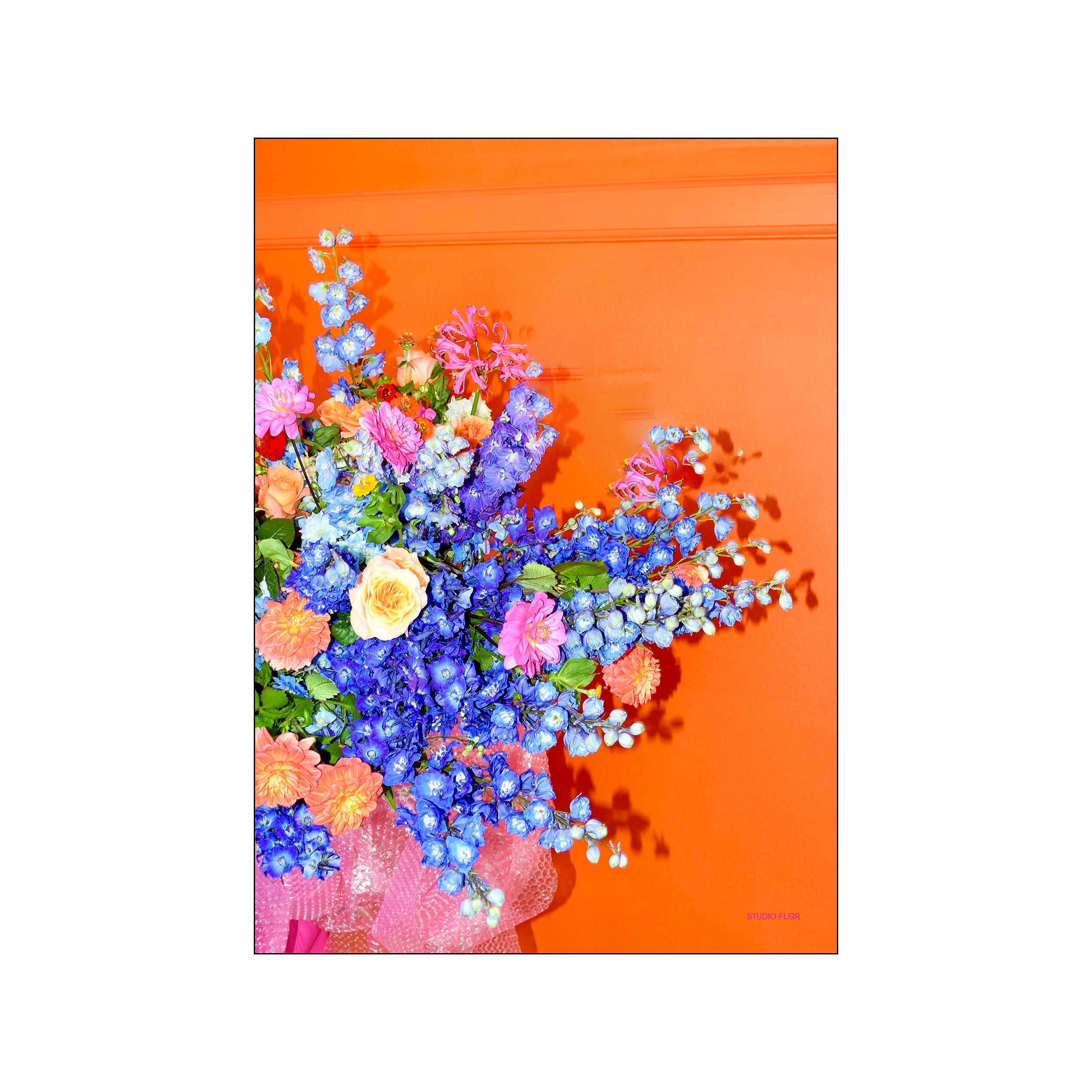 Studio FLØR floral bouquet with vivid blue and pink blooms on a bright orange background