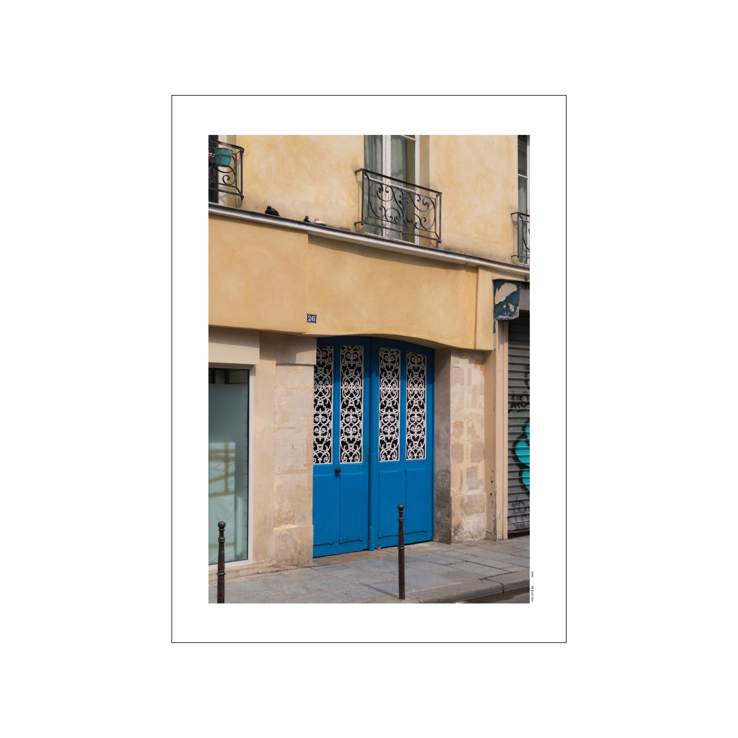 A vibrant blue Parisian door with ornate white scrollwork on glass, set against a textured, warm yellow building facade with stone accents, hinting at European elegance and street charm.