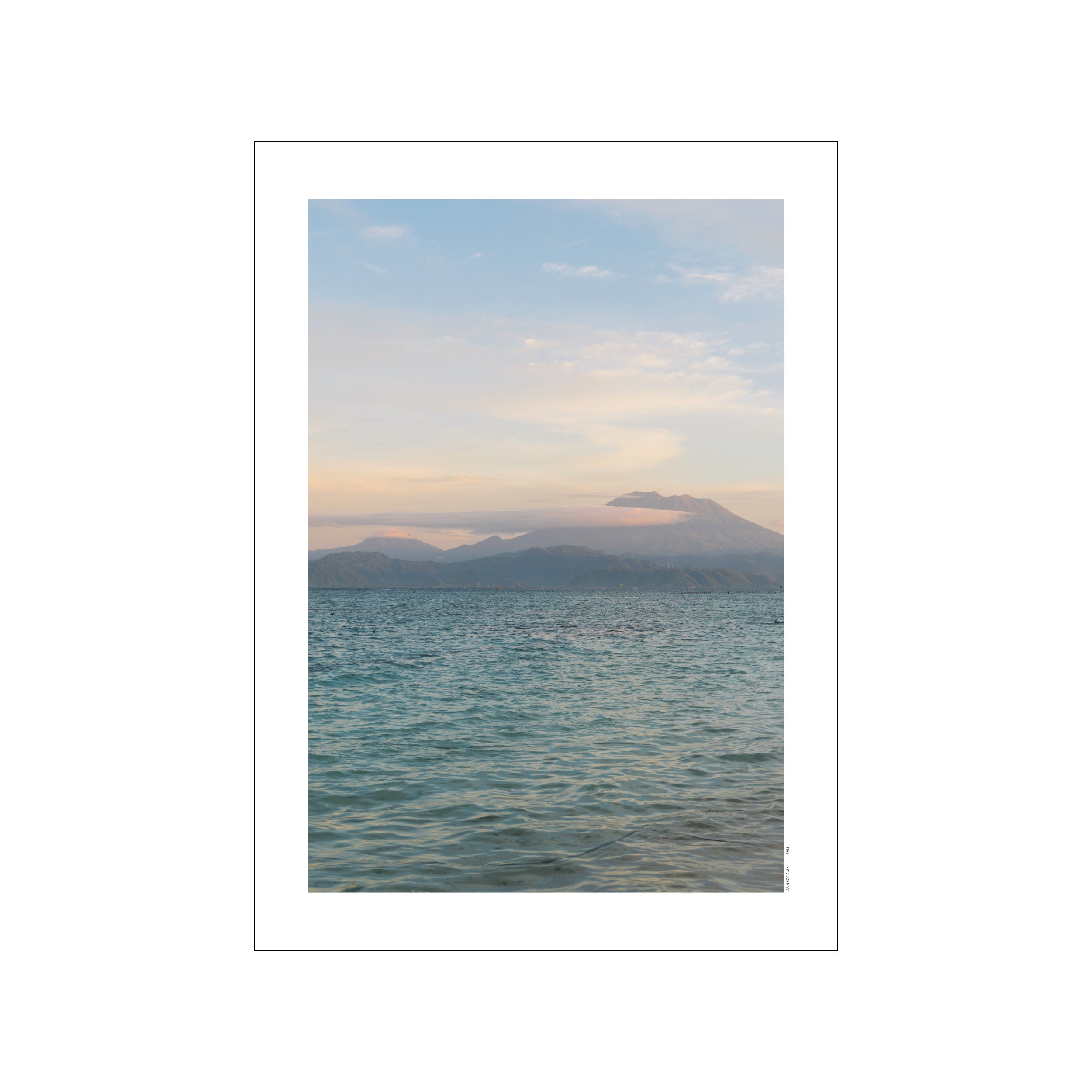A tranquil ocean view with gentle waves in the foreground, hazy distant mountains, and a soft, pastel-colored sky. Evokes a peaceful, coastal, and serene atmosphere.