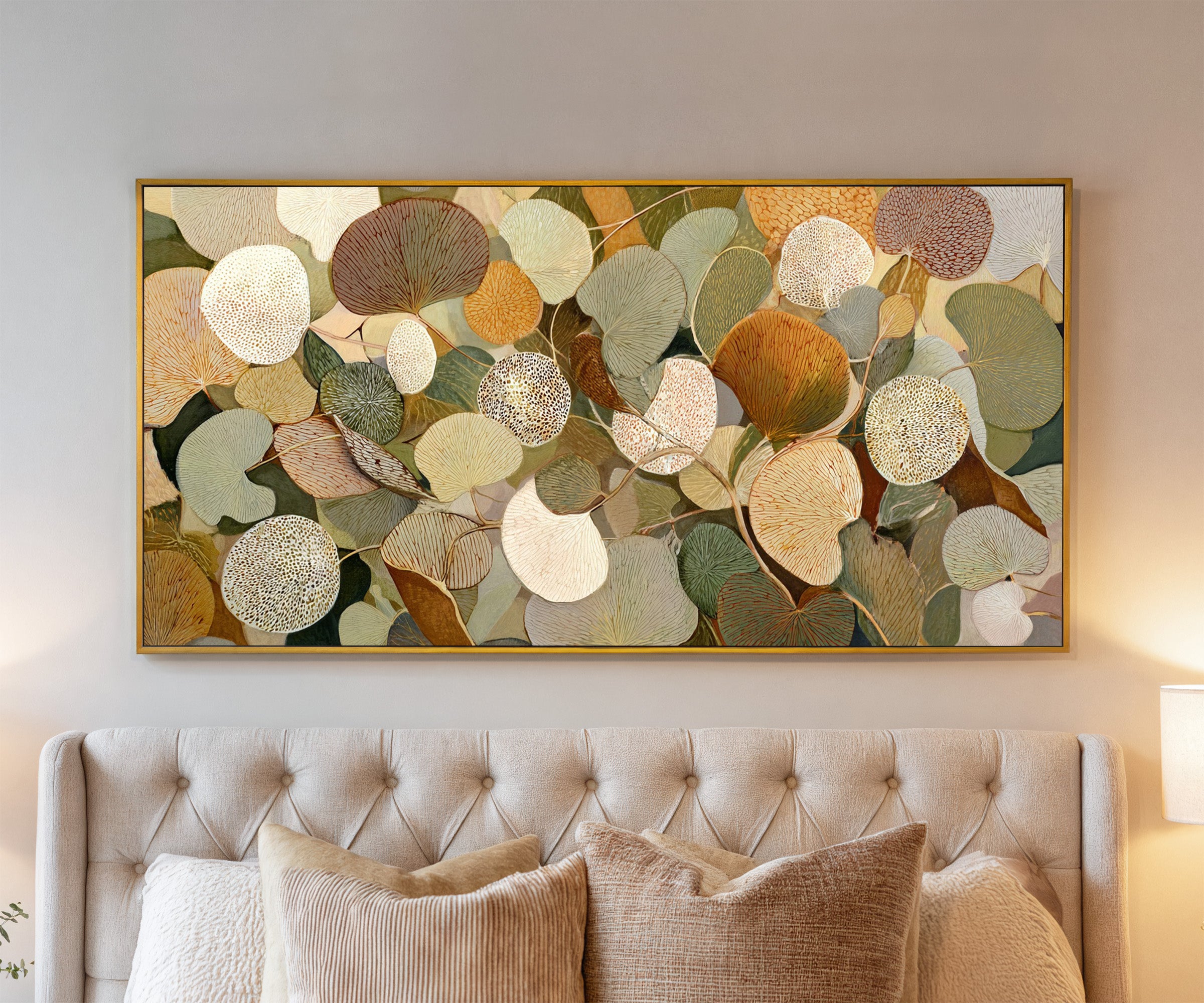 rounded leaf forms in olive, cream, gold, rust, canvas wall art in a gold frame above a bed