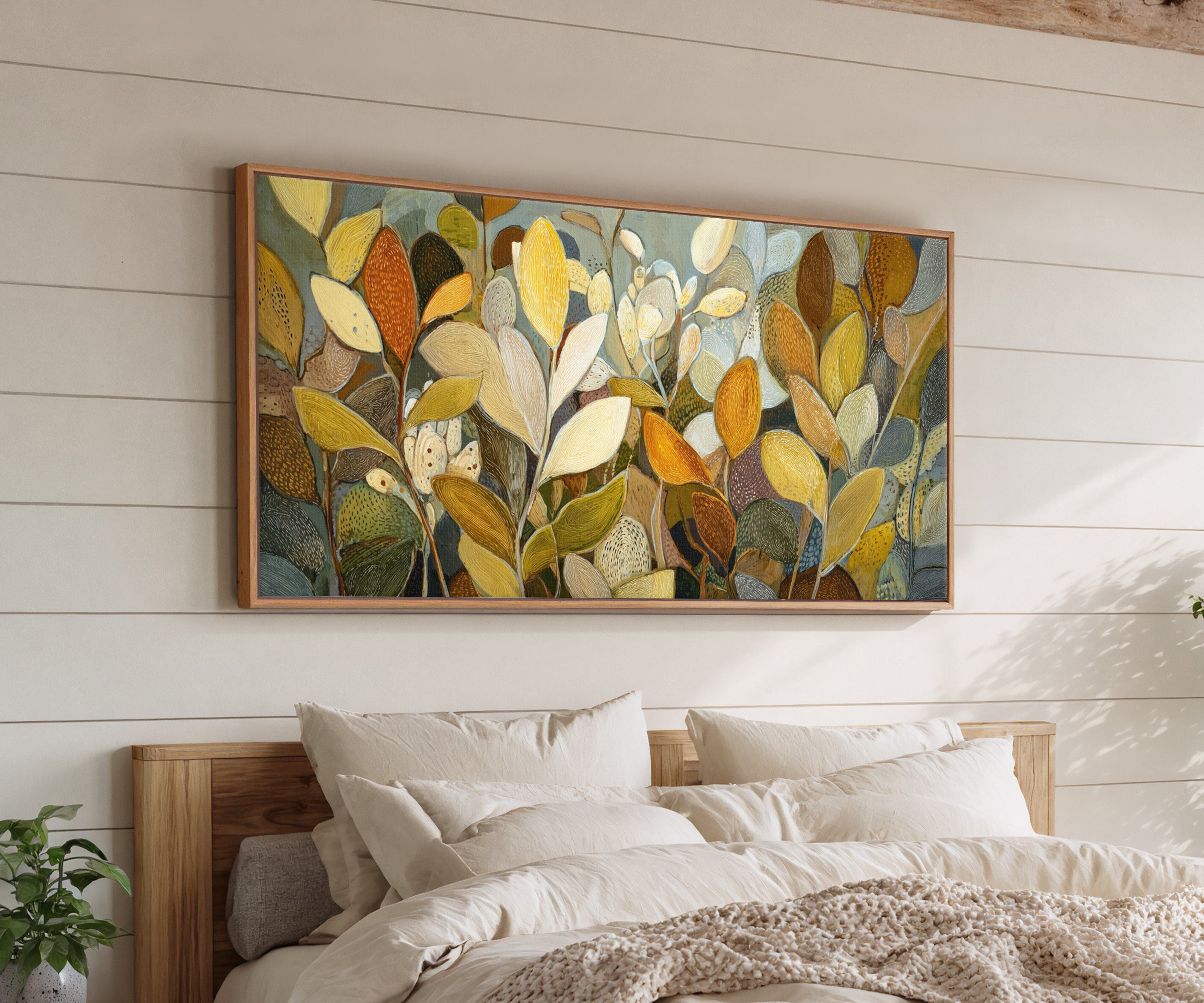 dense overlapping leaf forms in gold, cream, canvas wall art in an oak frame above a bed