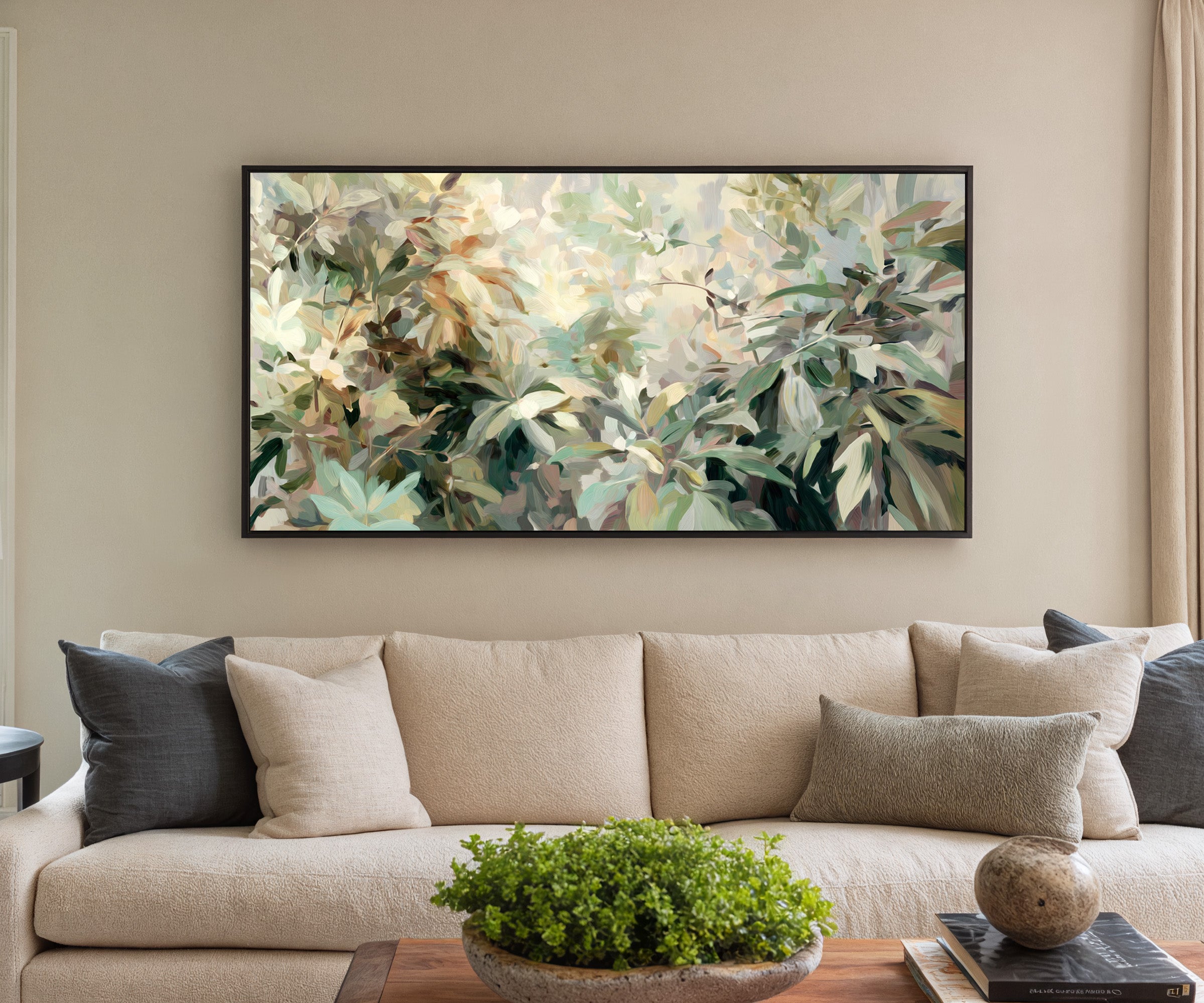 lush layered foliage in soft green, cream, and canvas wall art in a black frame in a styled room setting