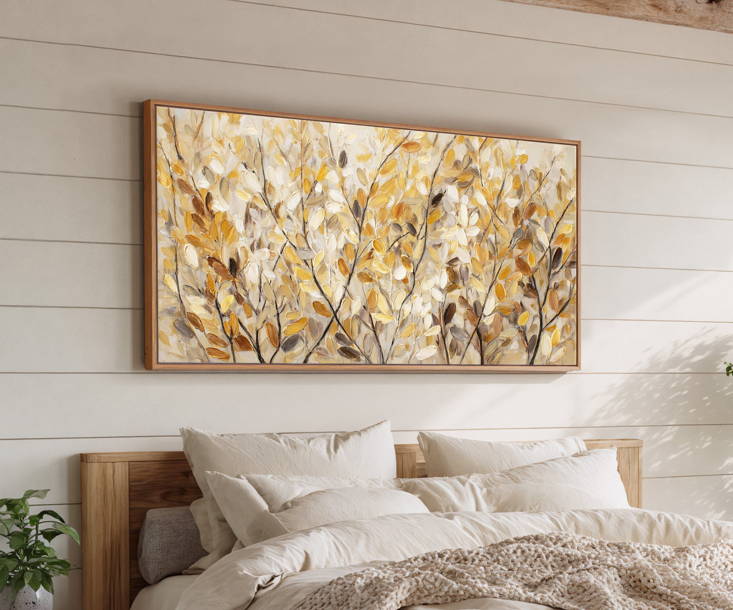 golden leaves and dark branching stems canvas wall art in an oak frame above a bed