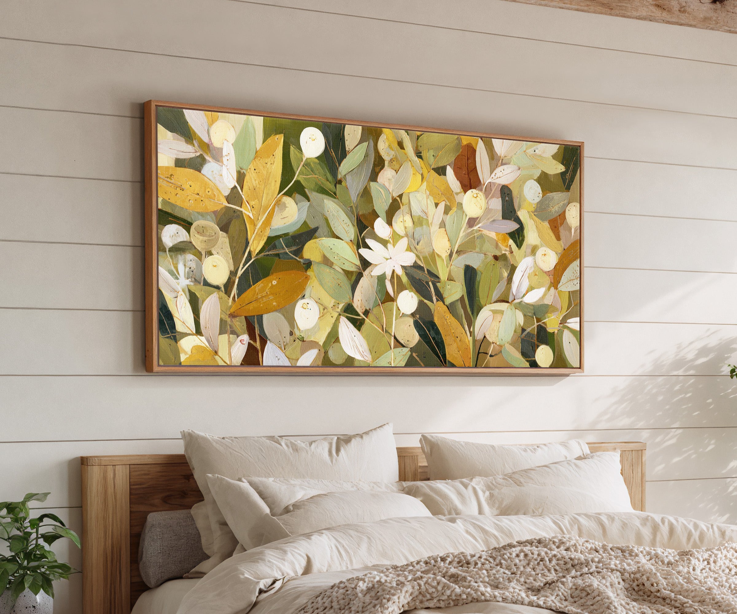 dense olive and gold leaf forms with pale canvas wall art in an oak frame above a bed