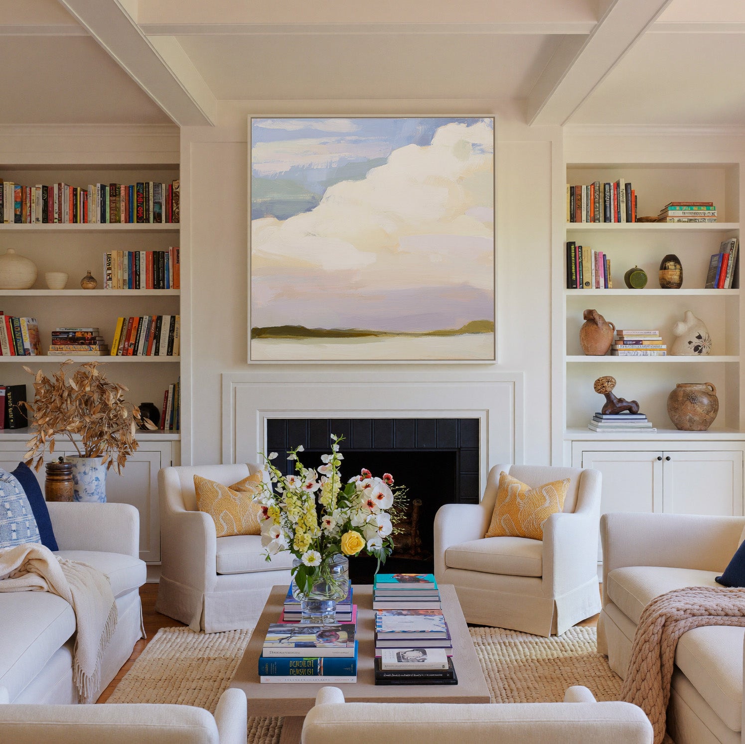 soft white clouds over pale blue and lavender canvas wall art in a white frame above a fireplace