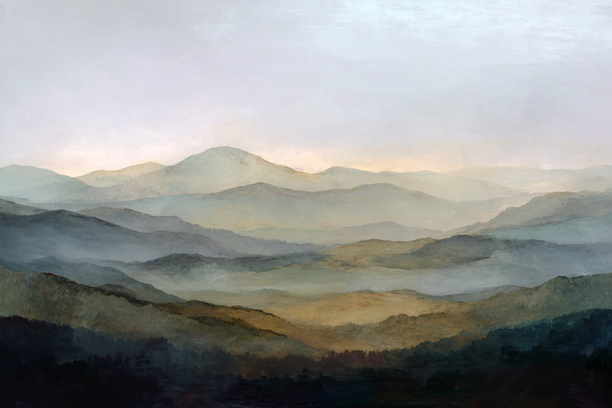 Layered blue gray mountain ridges with mist and a pale sky over dark foreground slopes