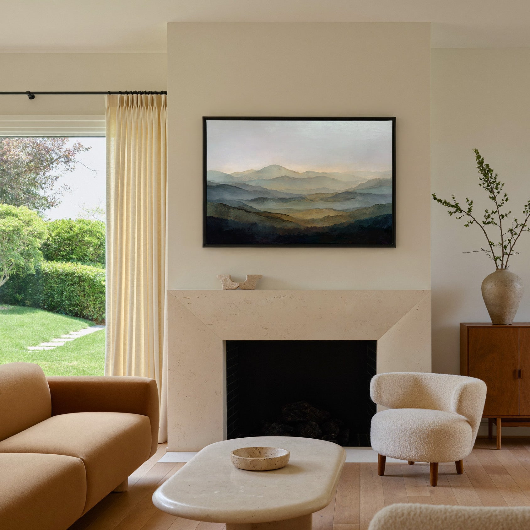 misty layered mountain landscape canvas wall art in a black frame above a mantel