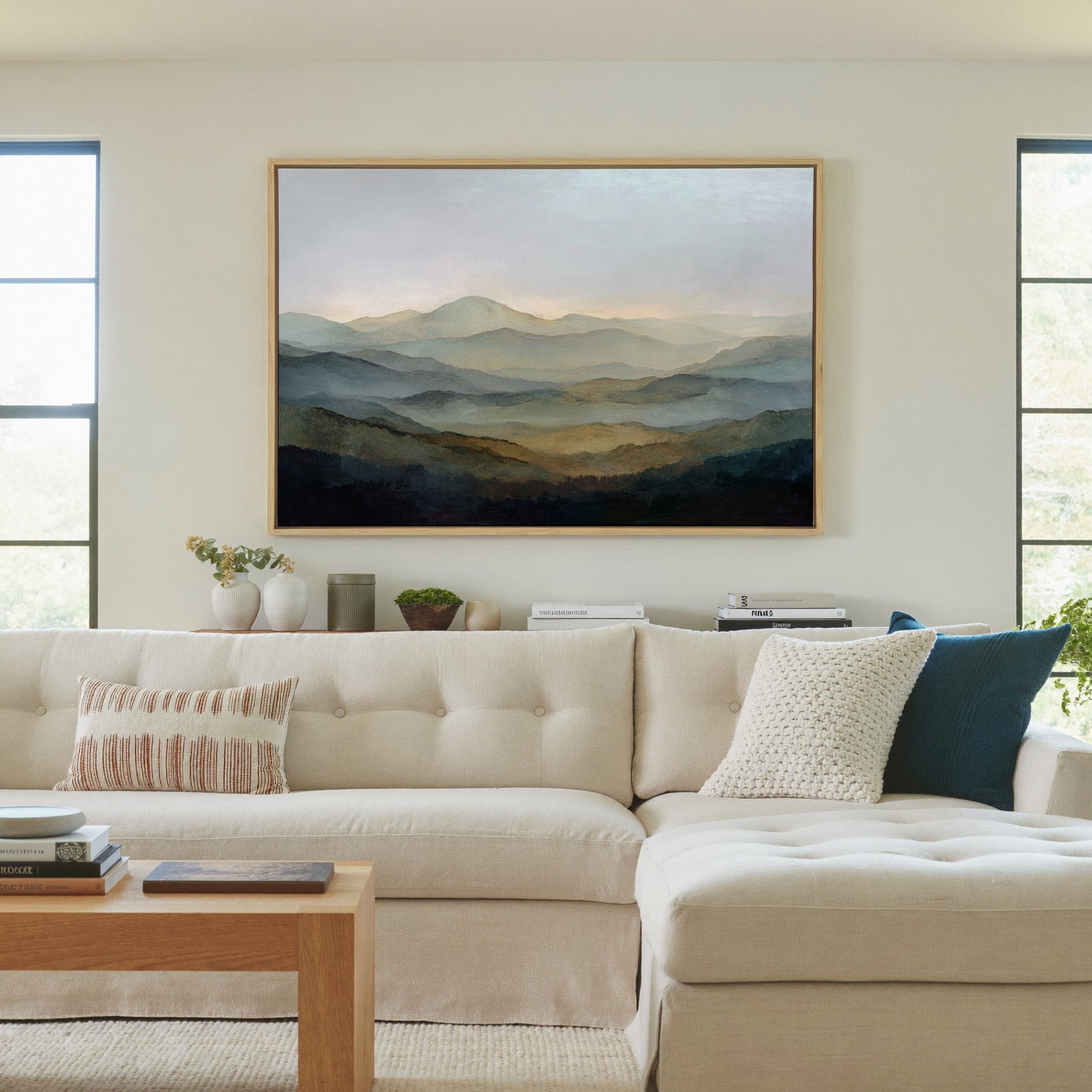 misty layered mountain landscape canvas wall art in a natural wood frame in a living room