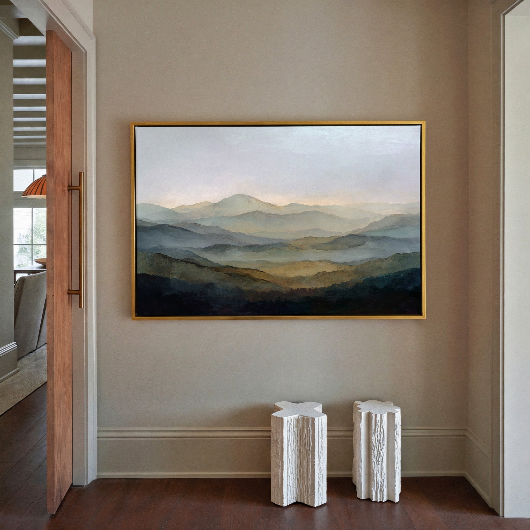 misty layered mountain landscape canvas wall art in a gold frame in a styled room setting