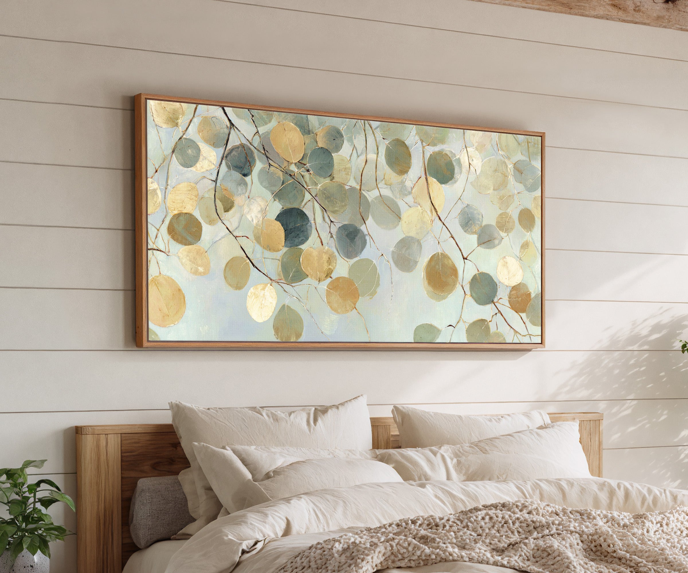 pale round leaves on branching stems canvas wall art in an oak frame above a bed