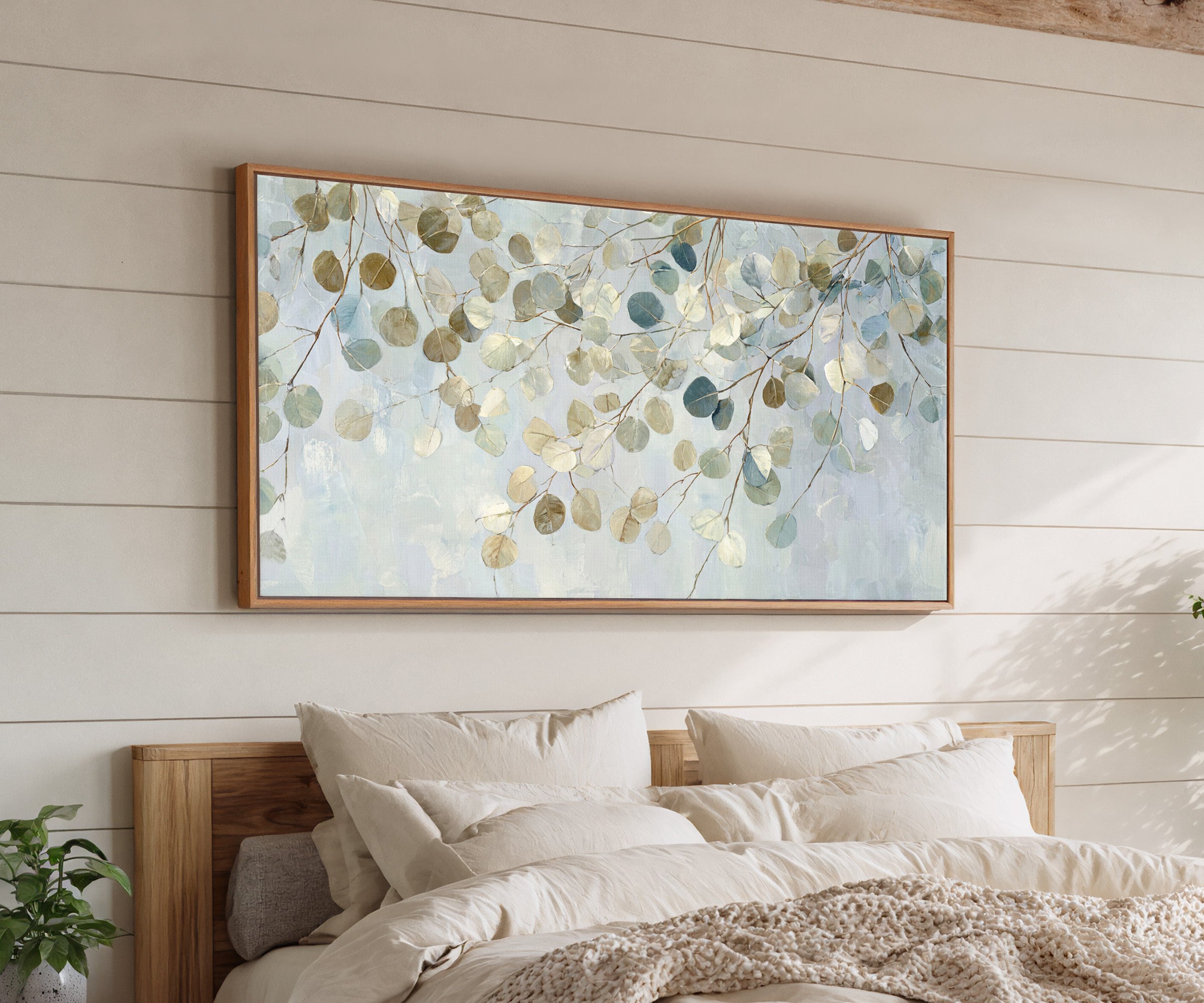 pale eucalyptus leaves on thin branching stems canvas wall art in an oak frame above a bed