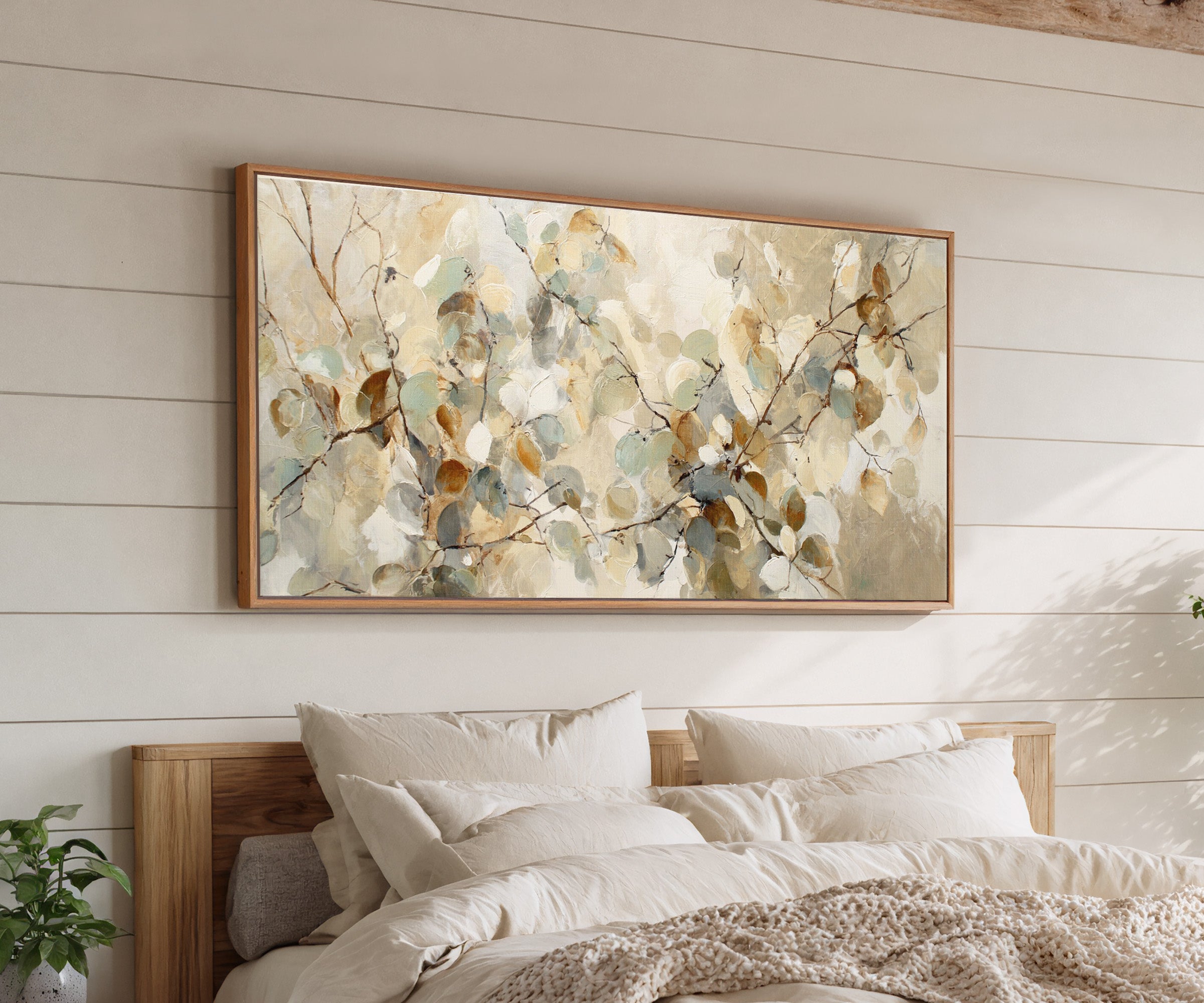 soft eucalyptus leaves in cream, sage, blue canvas wall art in an oak frame above a bed
