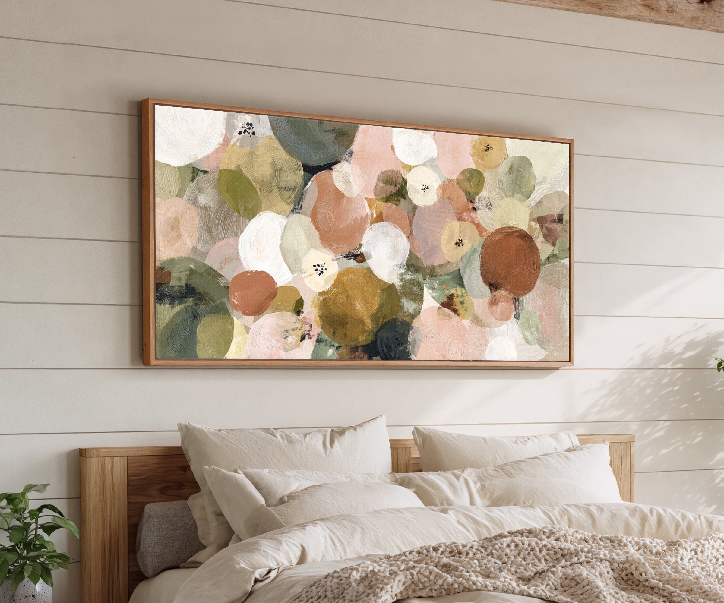 muted olive, blush, cream, and gold circles canvas wall art in an oak frame above a bed