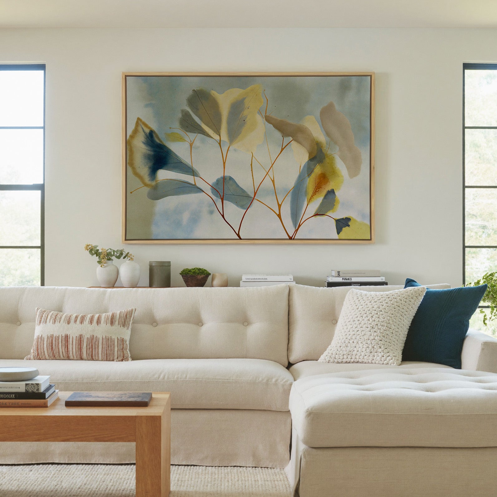 blue, cream, and yellow leaf branch canvas wall art in a natural wood frame in a living room