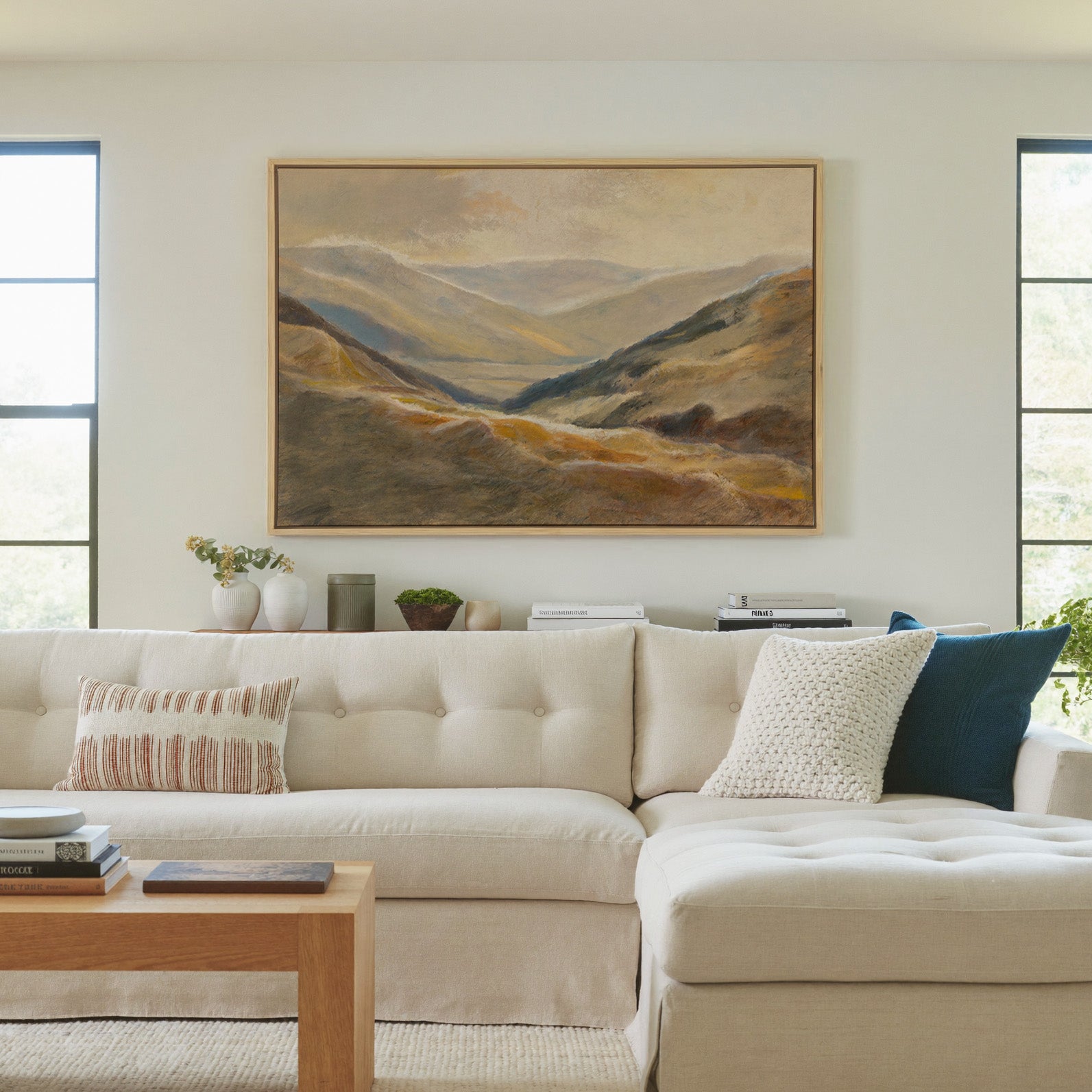 soft beige and blue mountain landscape canvas wall art in a natural wood frame in a living room