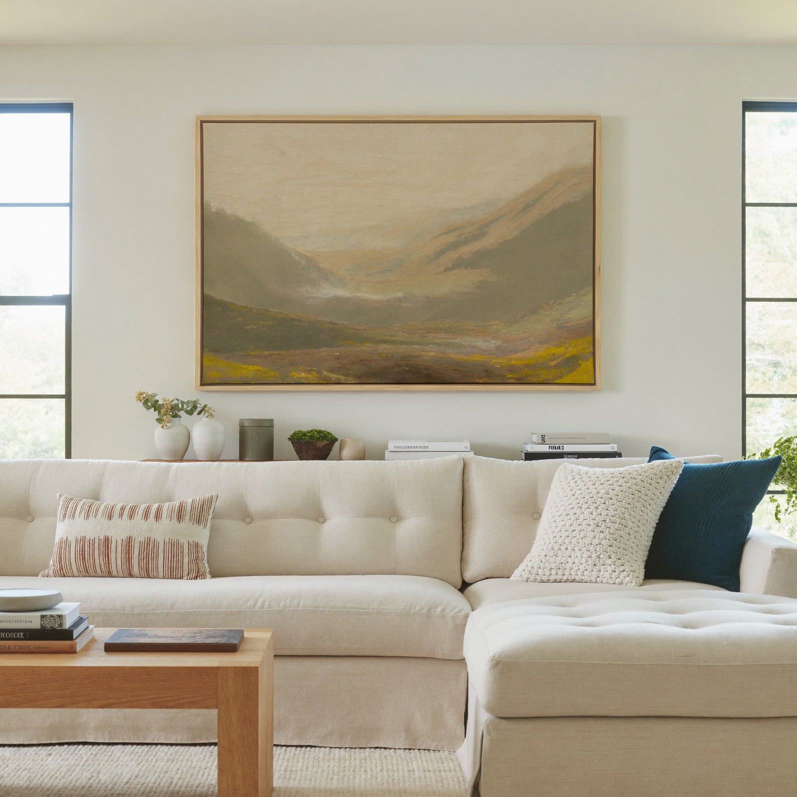 misty valley landscape with ochre hills and a canvas wall art in a natural wood frame in a living room