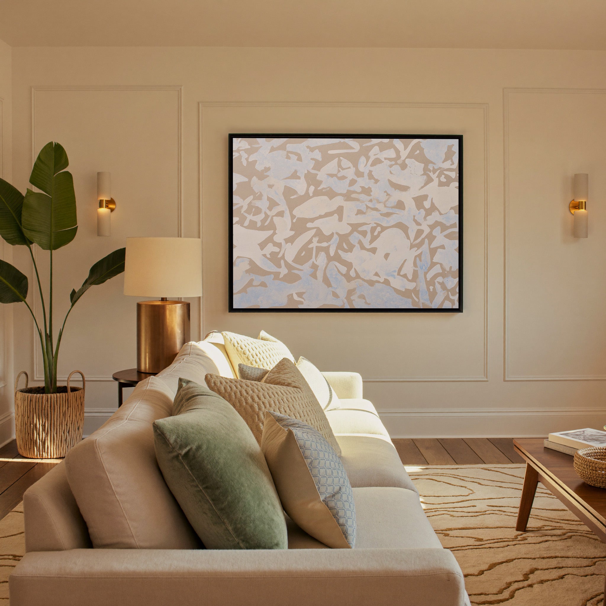 soft beige and pale blue abstract canvas wall art in a black frame in a styled room setting
