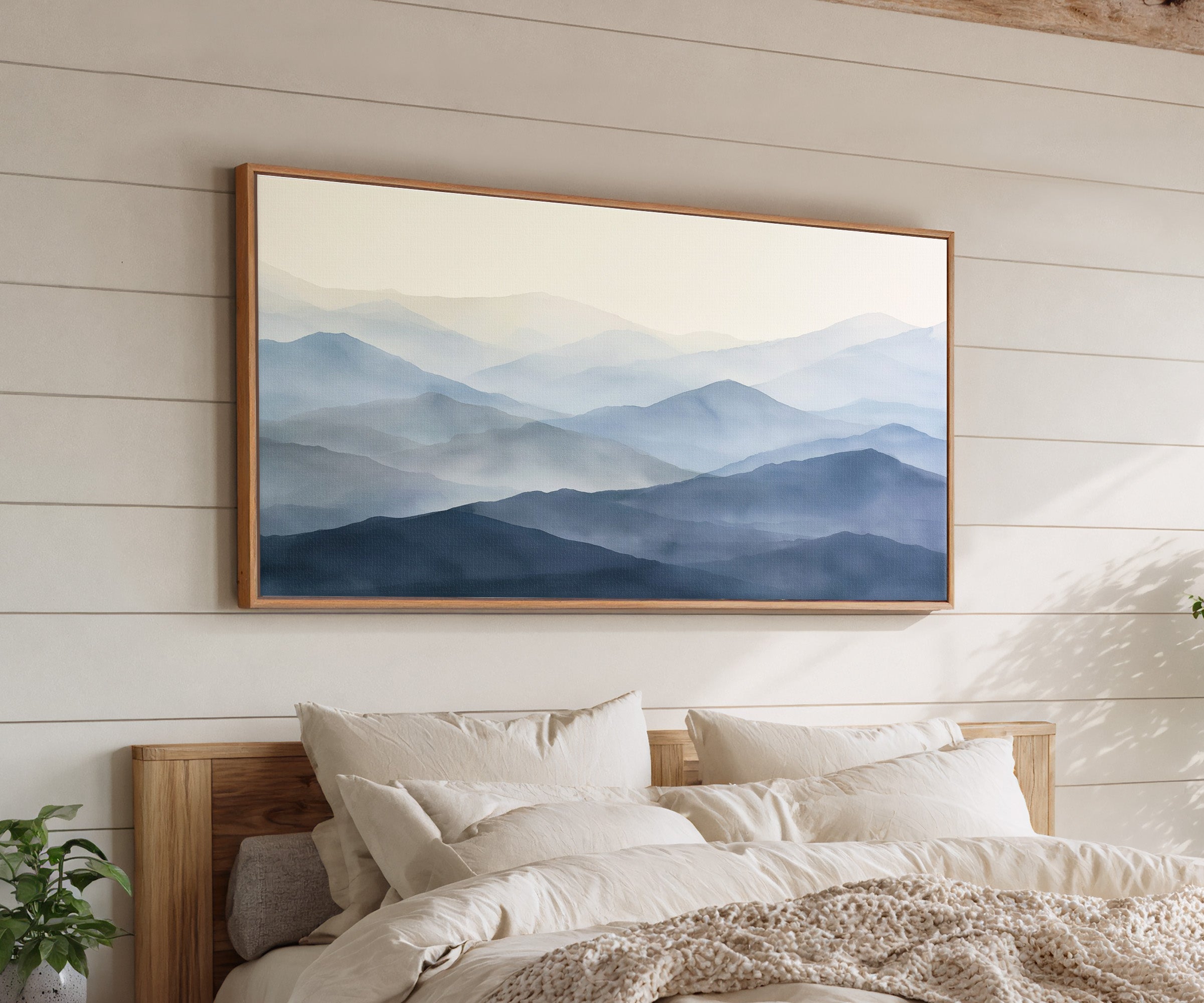 soft blue mountain layers canvas wall art in an oak frame above a bed, with clear frame and room context