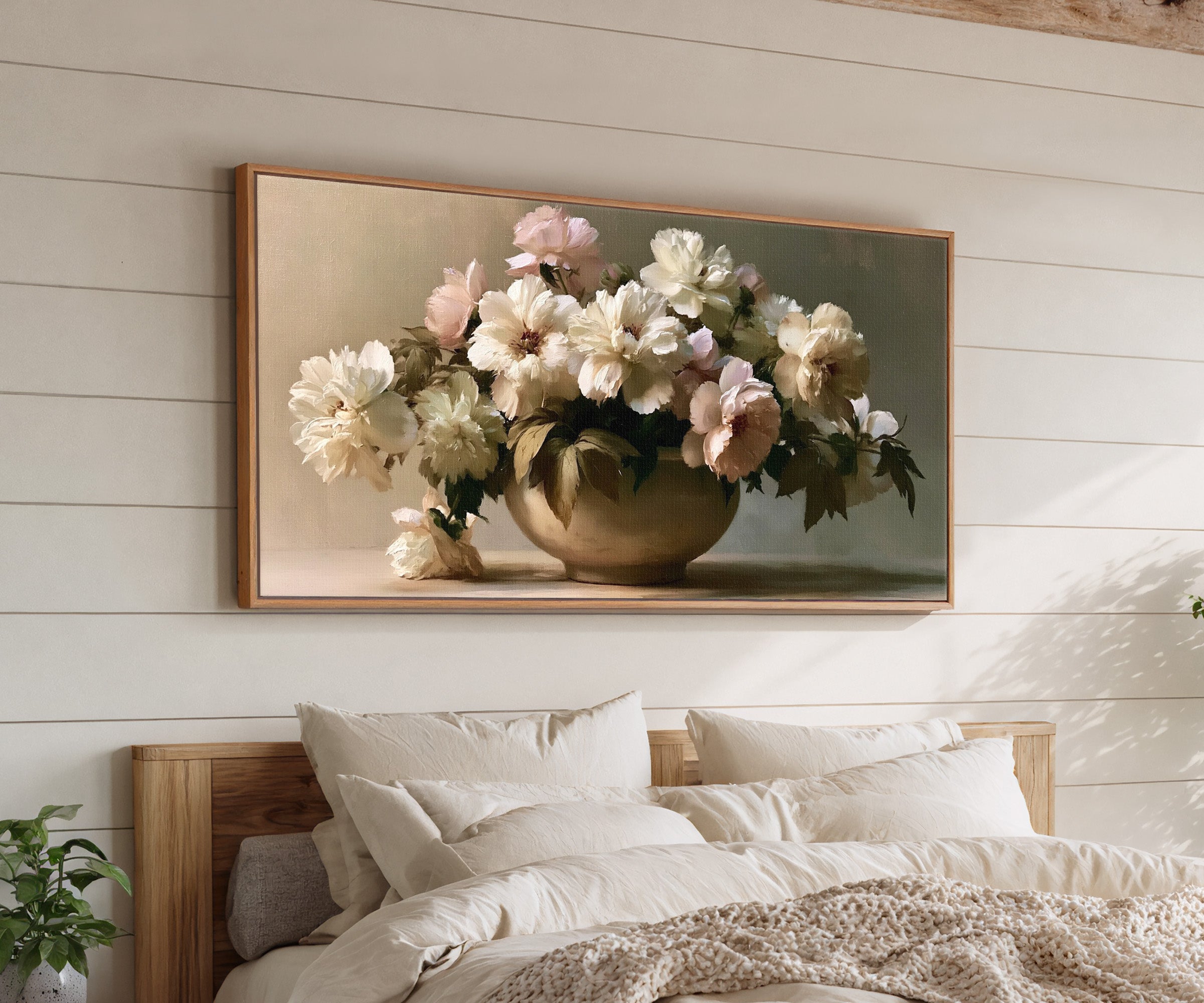 cream and pale blush floral still life canvas wall art in an oak frame above a bed