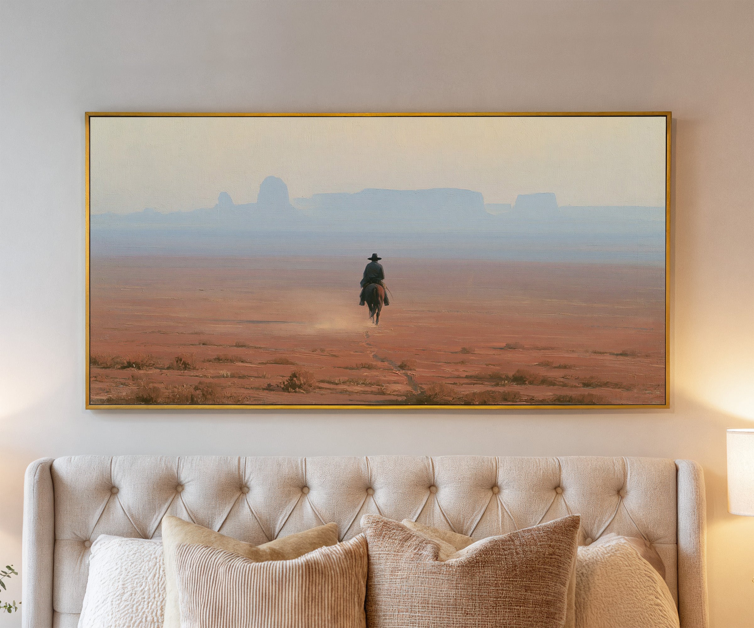 lone rider across a red desert plain with pale canvas wall art in a gold frame above a bed