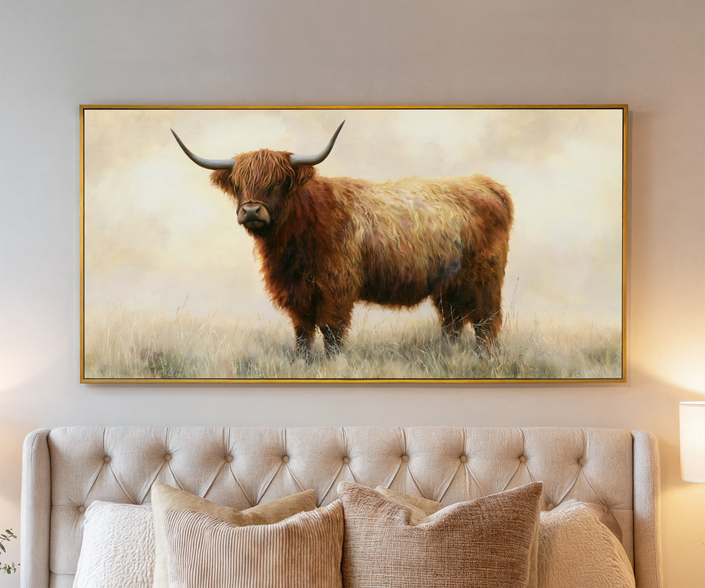 warm brown highland cow in pale dry grass canvas wall art in a gold frame above a bed