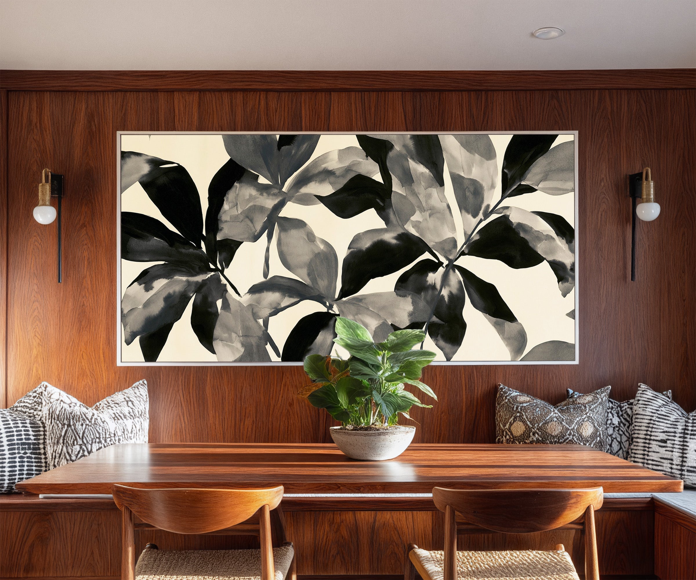 overlapping black and gray leaf shapes on cream canvas wall art in a white frame in a styled room setting