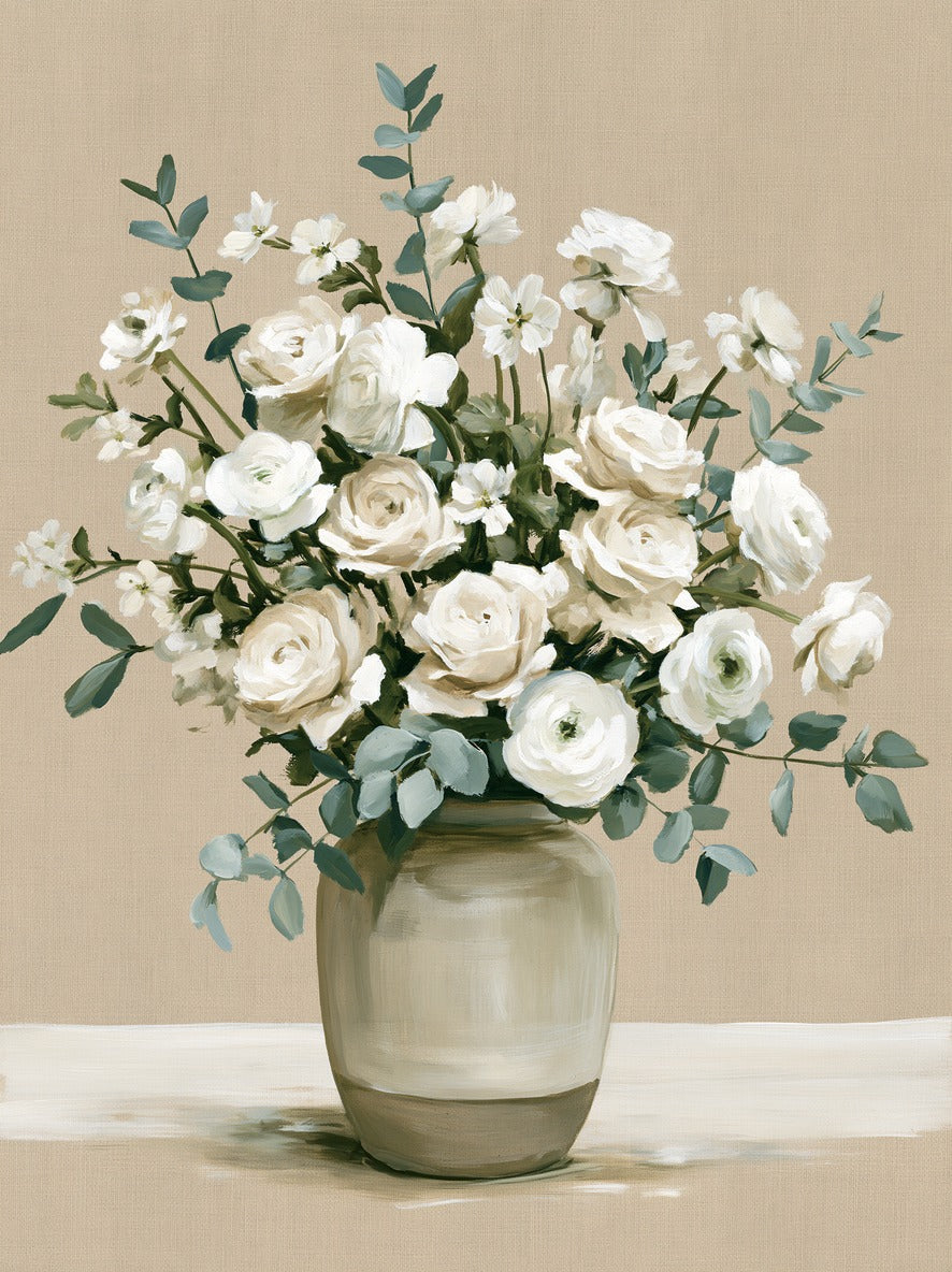 White roses and ranunculus in a glass vase, with blue-green leaves spreading across a beige ground