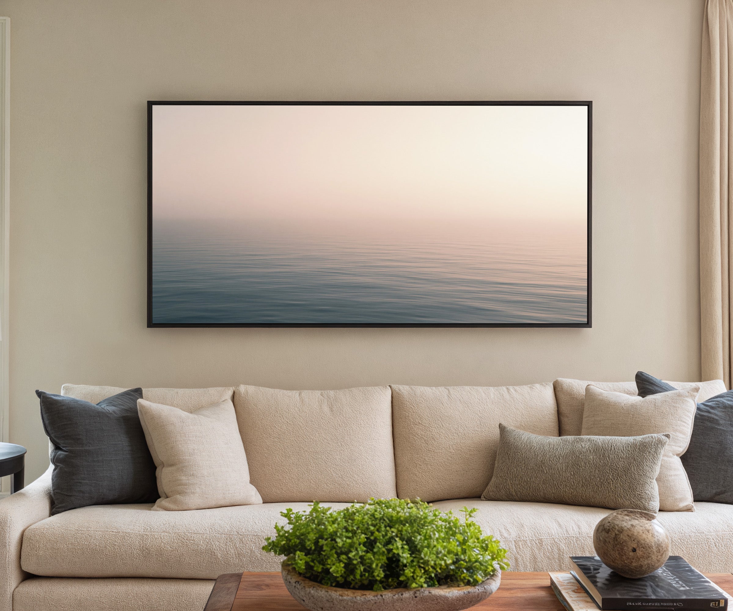 soft blush and blue seascape canvas wall art in a black frame in a styled room setting