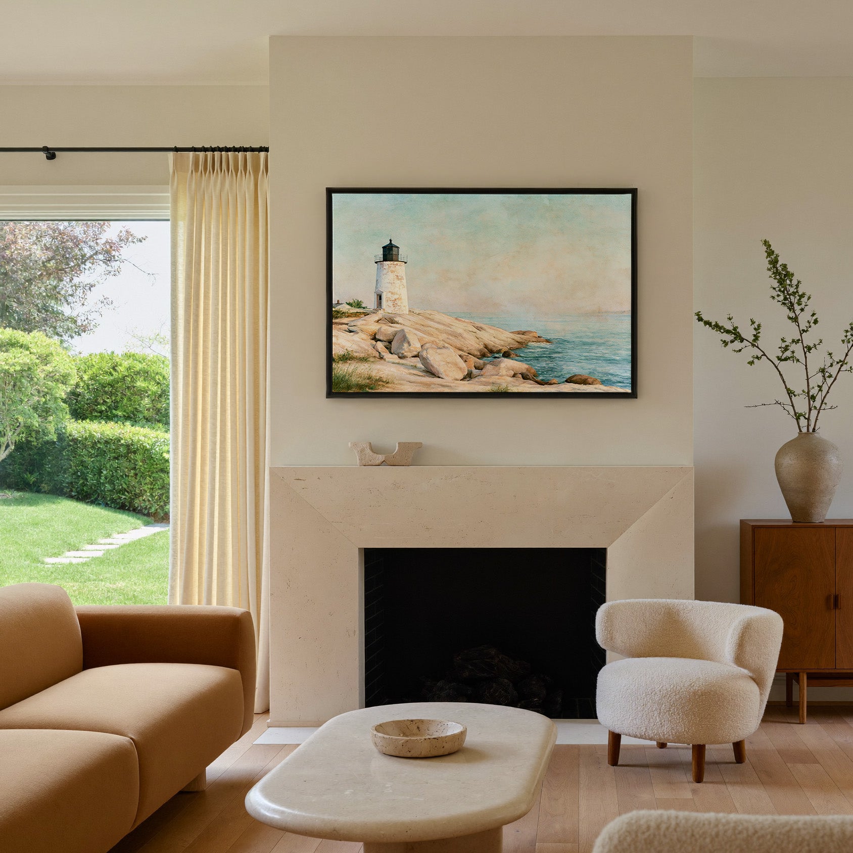 weathered white lighthouse on pale rock above canvas wall art in a black frame above a mantel