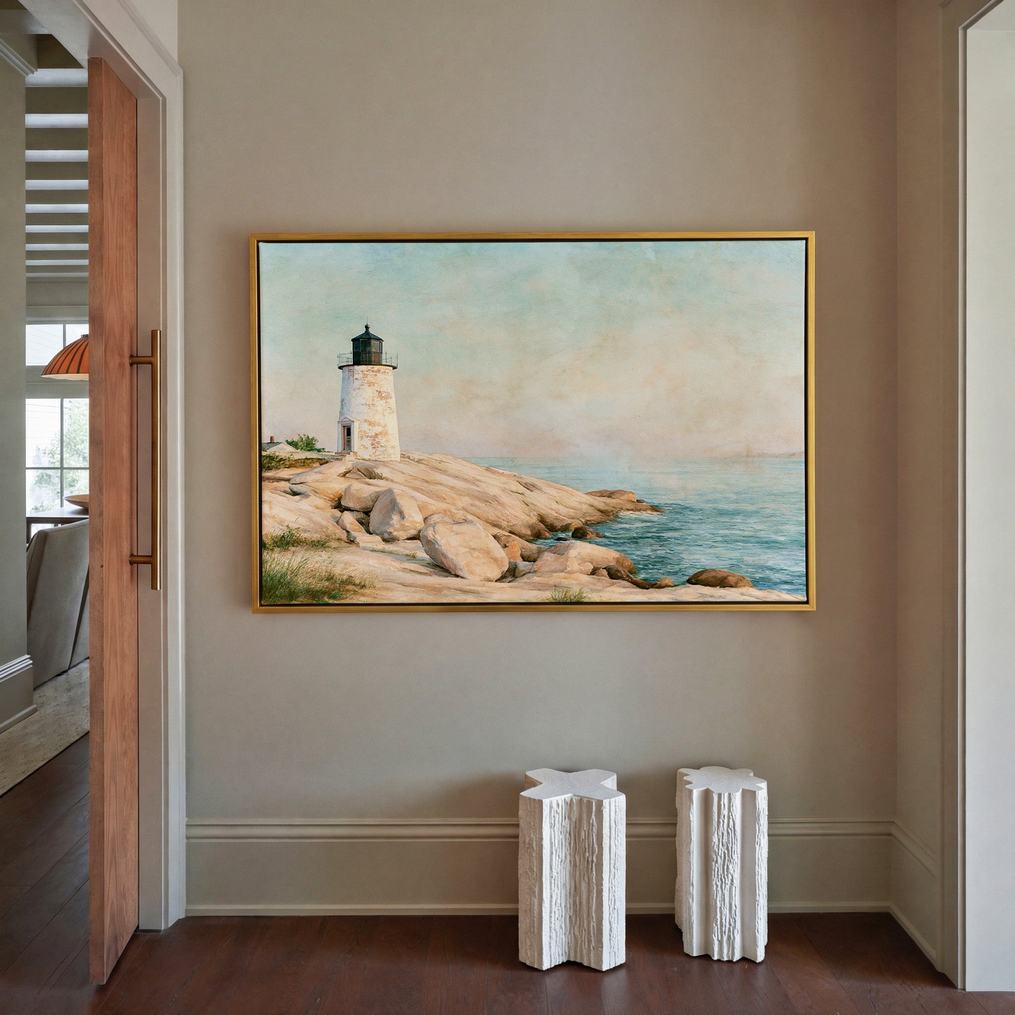weathered white lighthouse on pale rock above canvas wall art in a gold frame in a styled room setting