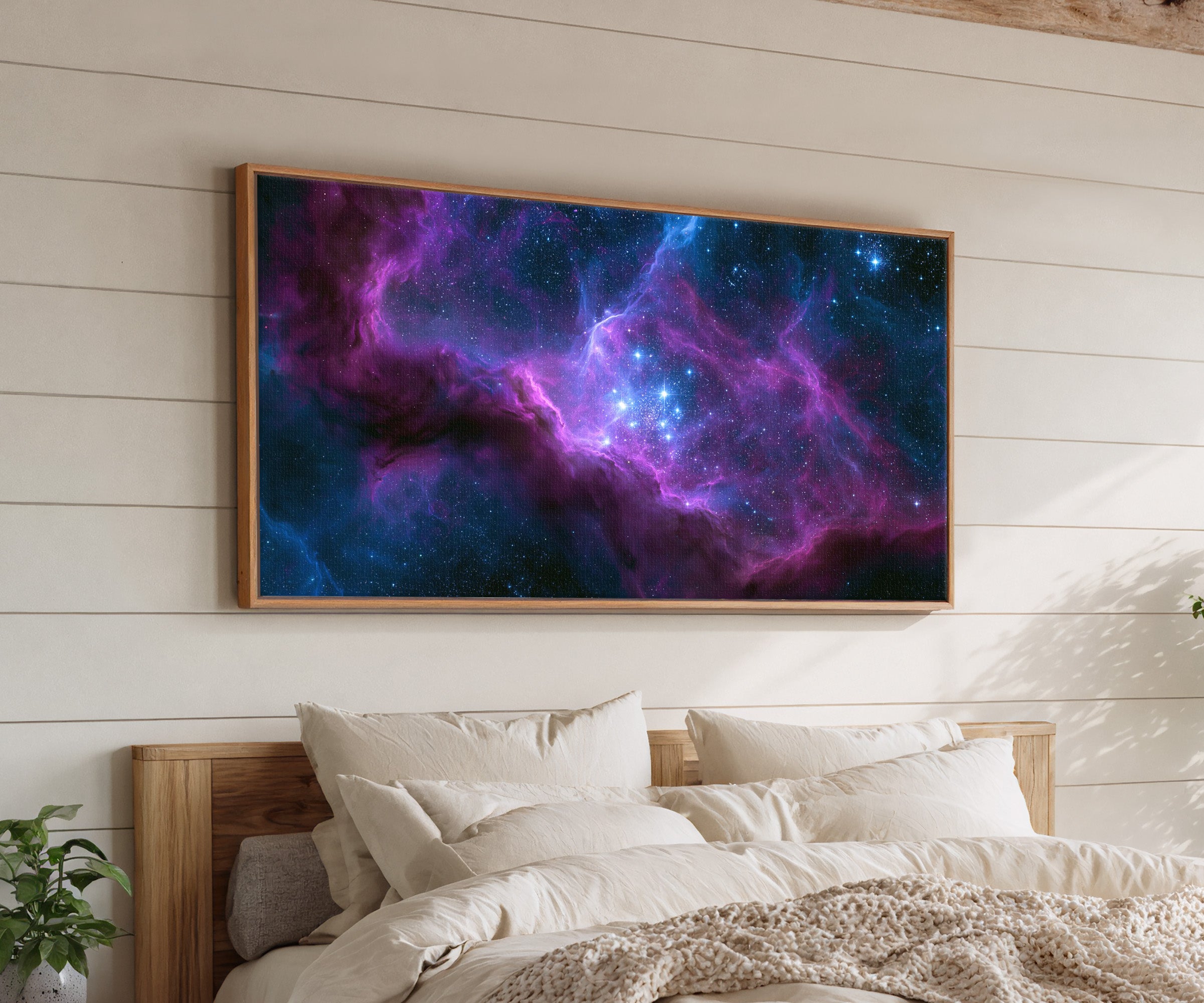 violet and blue nebula with bright star cluster canvas wall art in an oak frame above a bed
