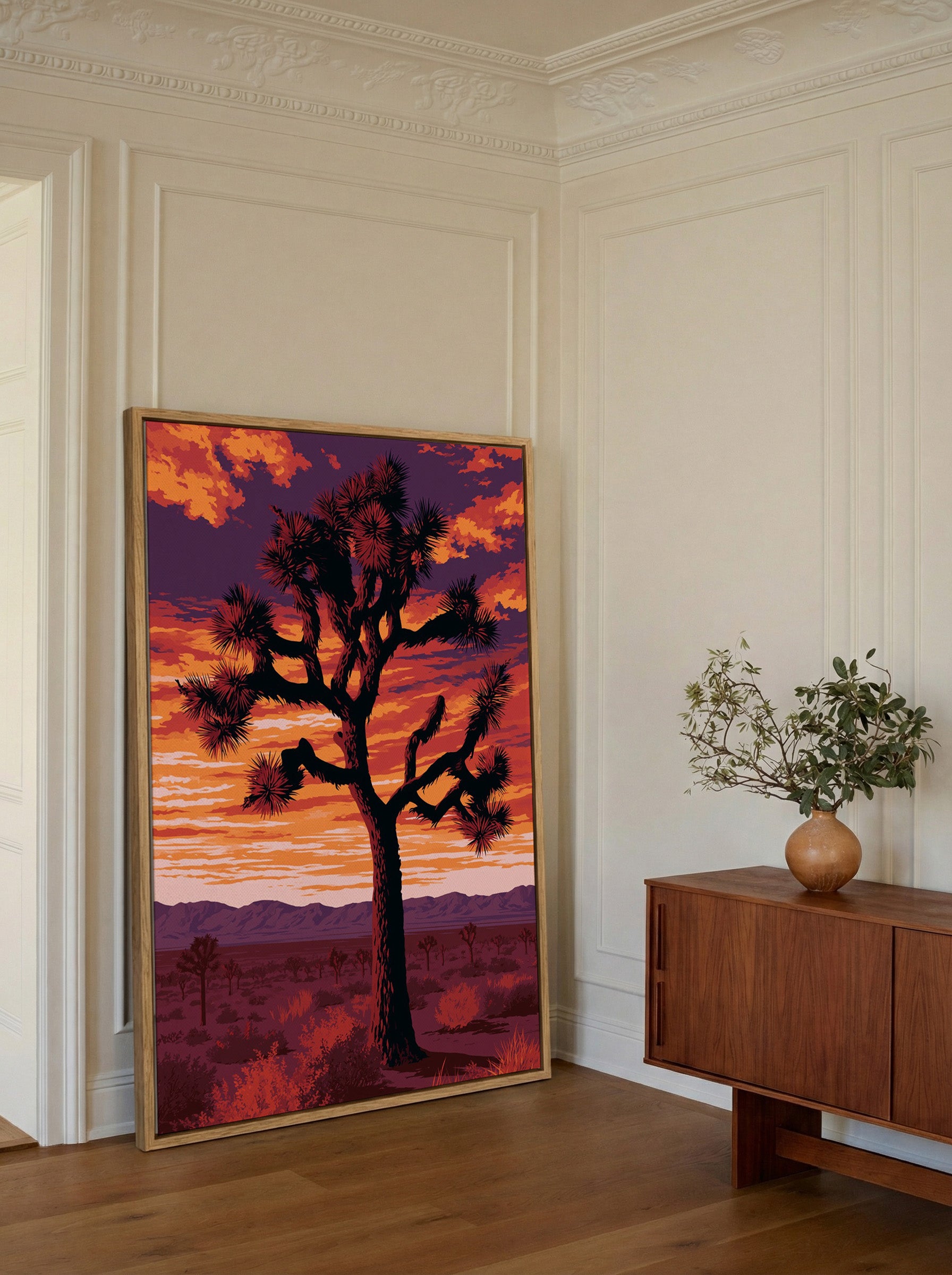 silhouetted joshua tree at sunset with orange canvas wall art in an oak frame in a styled room setting