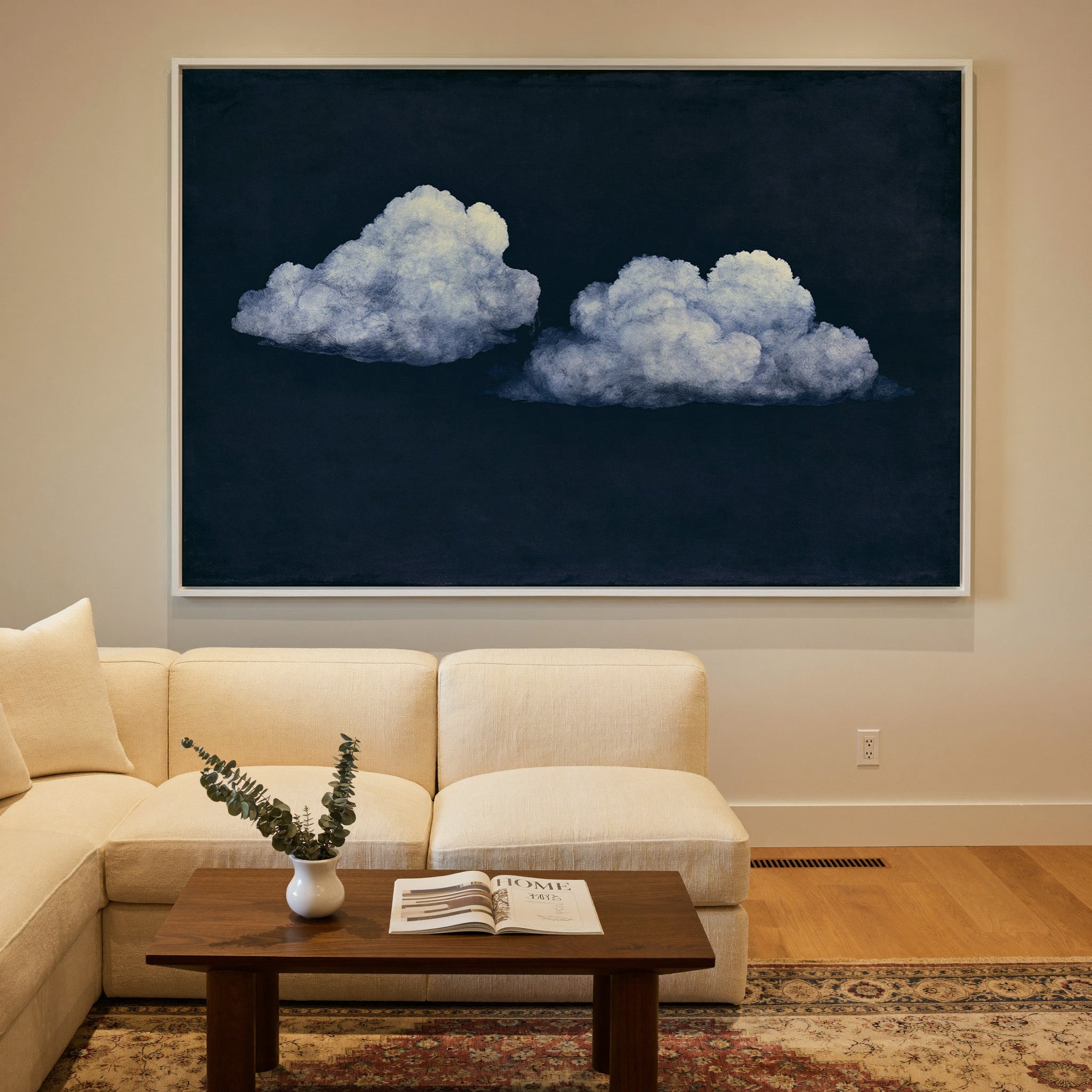 two pale clouds on a deep navy field canvas wall art in a white frame in a styled room setting