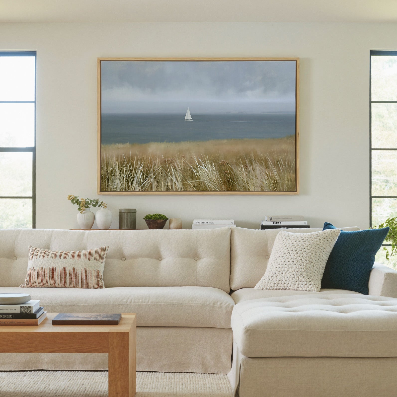 distant white sailboat on a gray blue sea canvas wall art in a natural wood frame in a living room