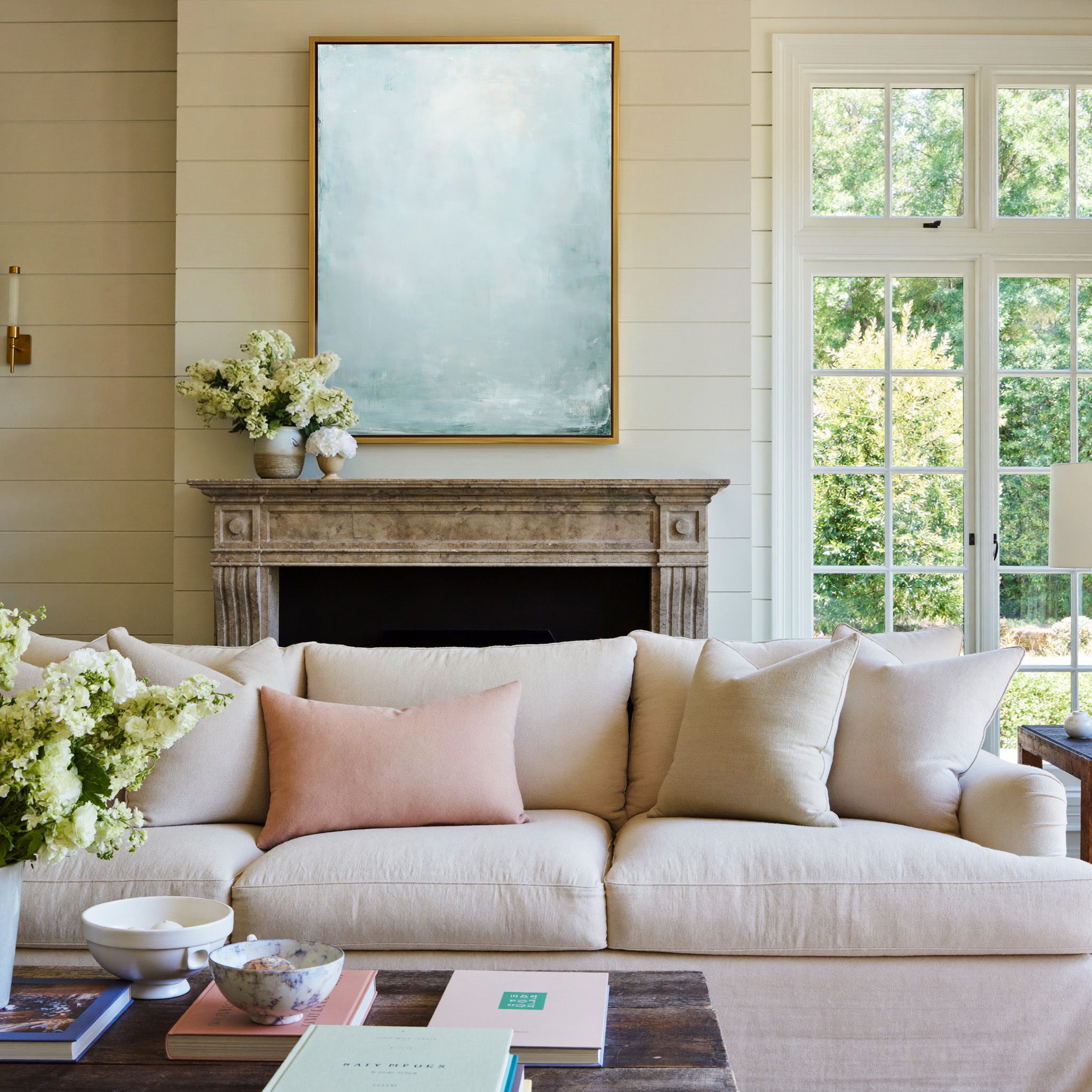 pale blue and white abstract with soft vertical canvas wall art in a gold frame above a mantel