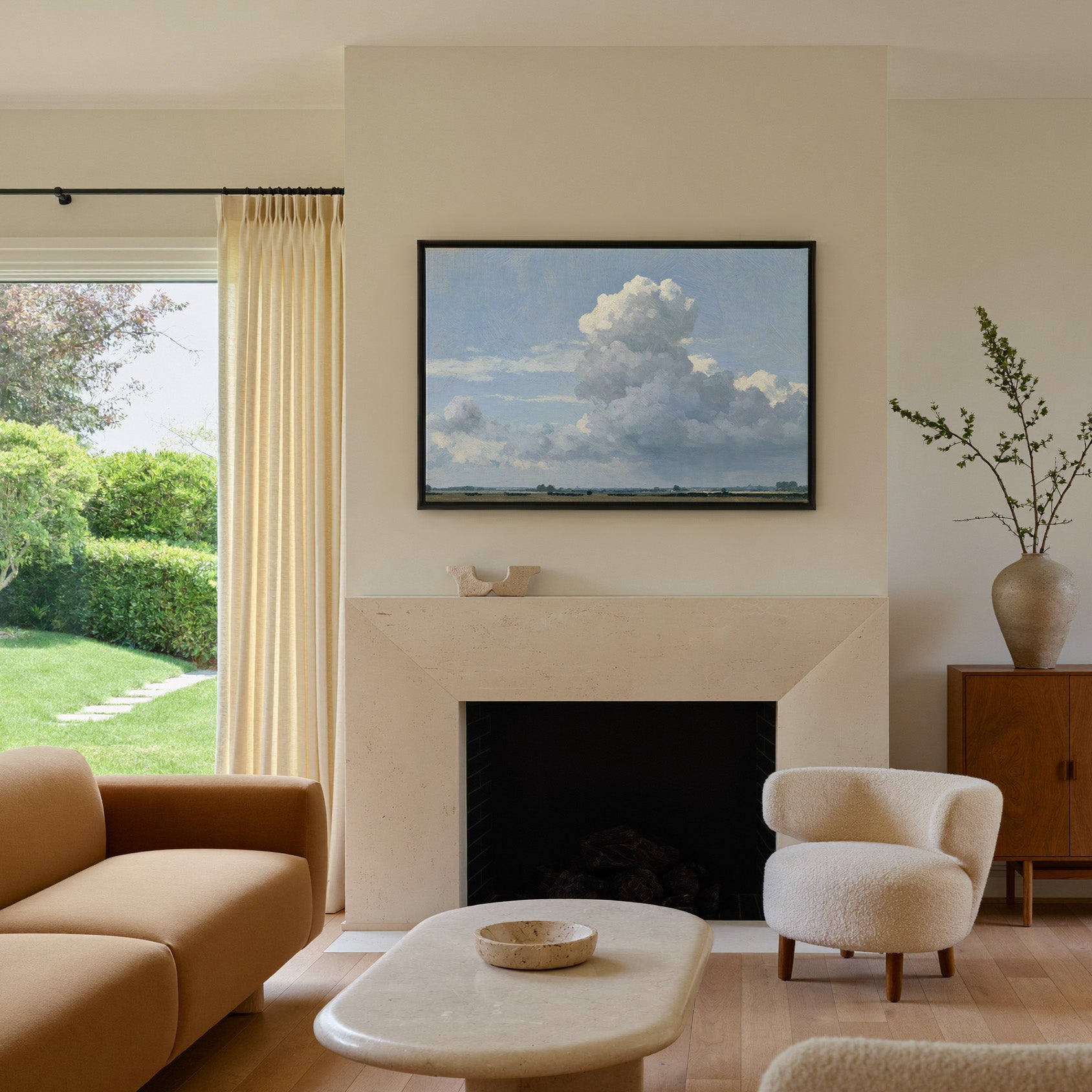 vast blue sky with towering white cloud over a canvas wall art in a black frame above a mantel