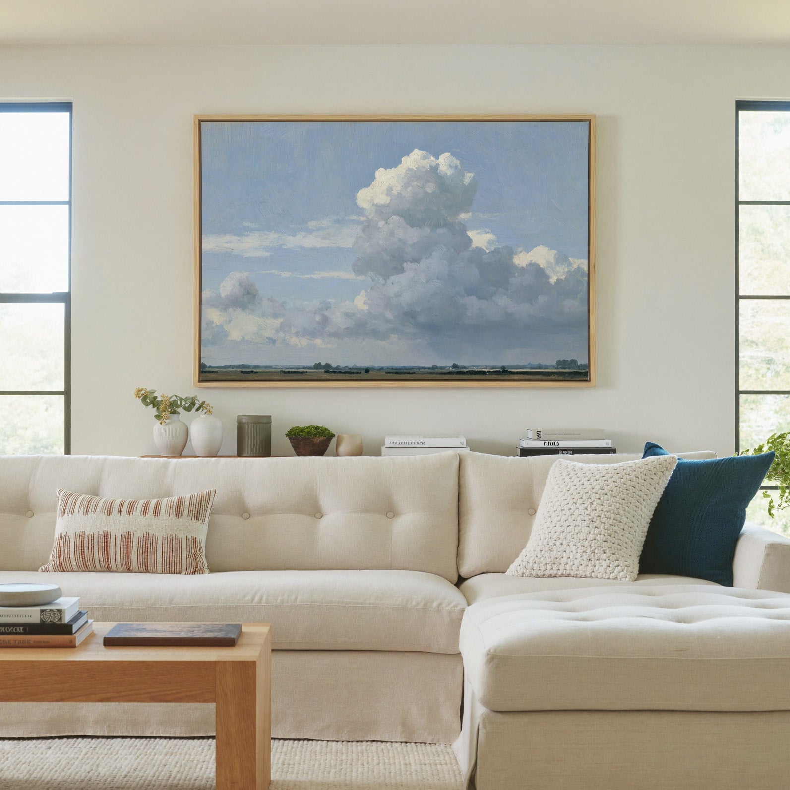 vast blue sky with towering white cloud over a canvas wall art in a natural wood frame in a living room