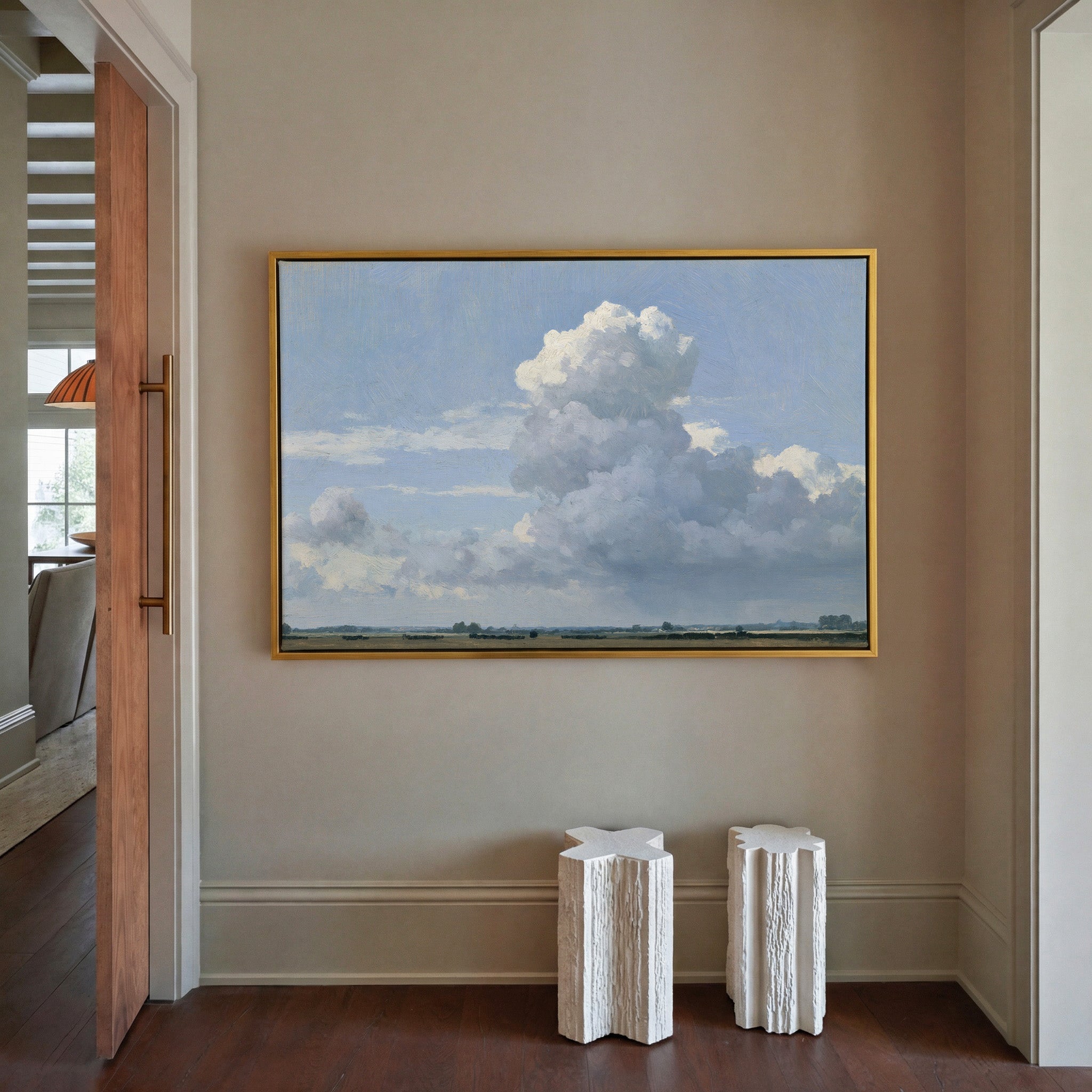 vast blue sky with towering white cloud over a canvas wall art in a gold frame in a styled room setting