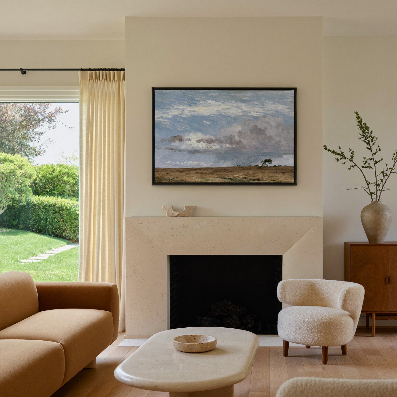 low field beneath immense rain clouds canvas wall art in a black frame above a mantel