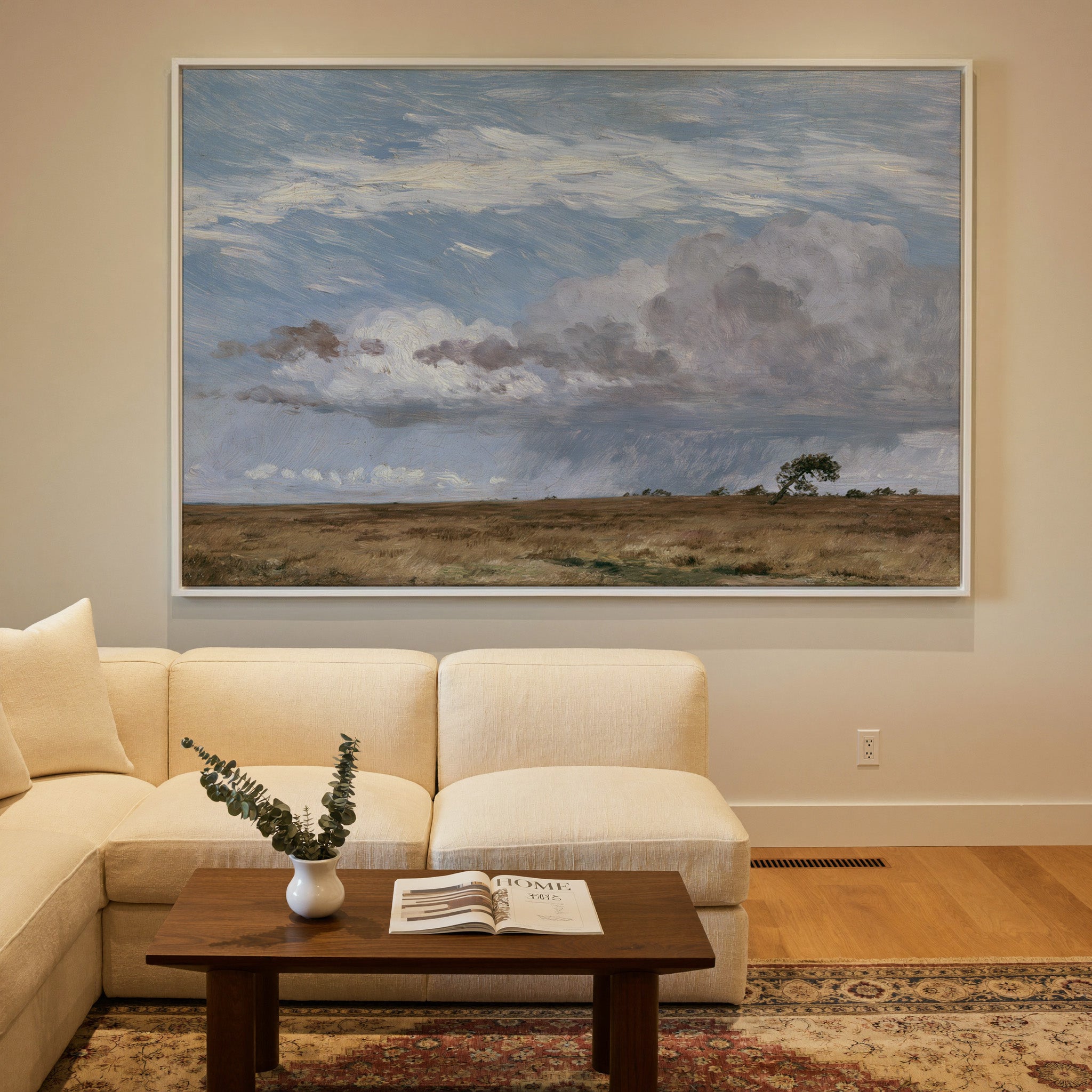 low field beneath immense rain clouds canvas wall art in a white frame in a styled room setting