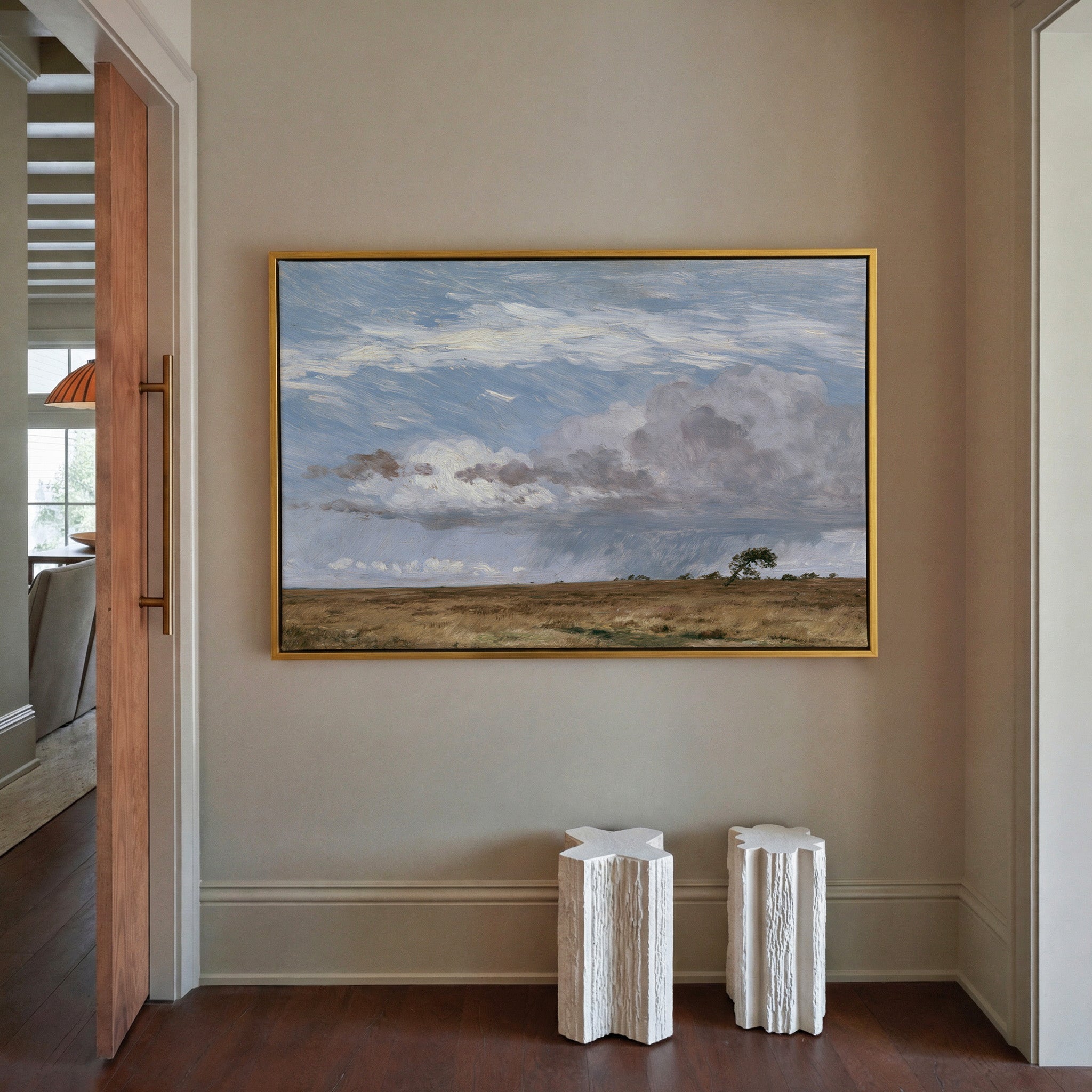 low field beneath immense rain clouds canvas wall art in a gold frame in a styled room setting